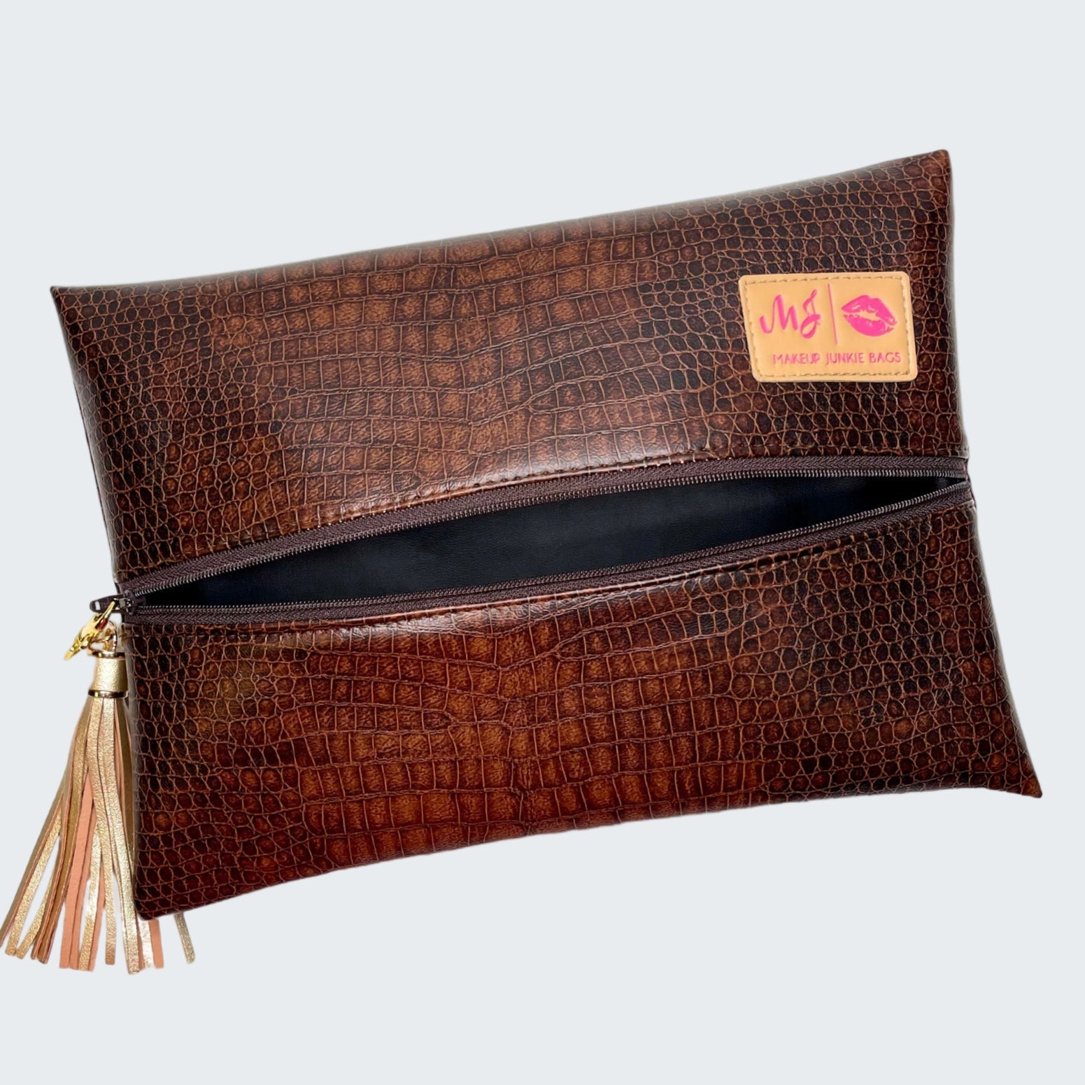 Brown crocodile-patterned clutch bag with a tassel on a white background