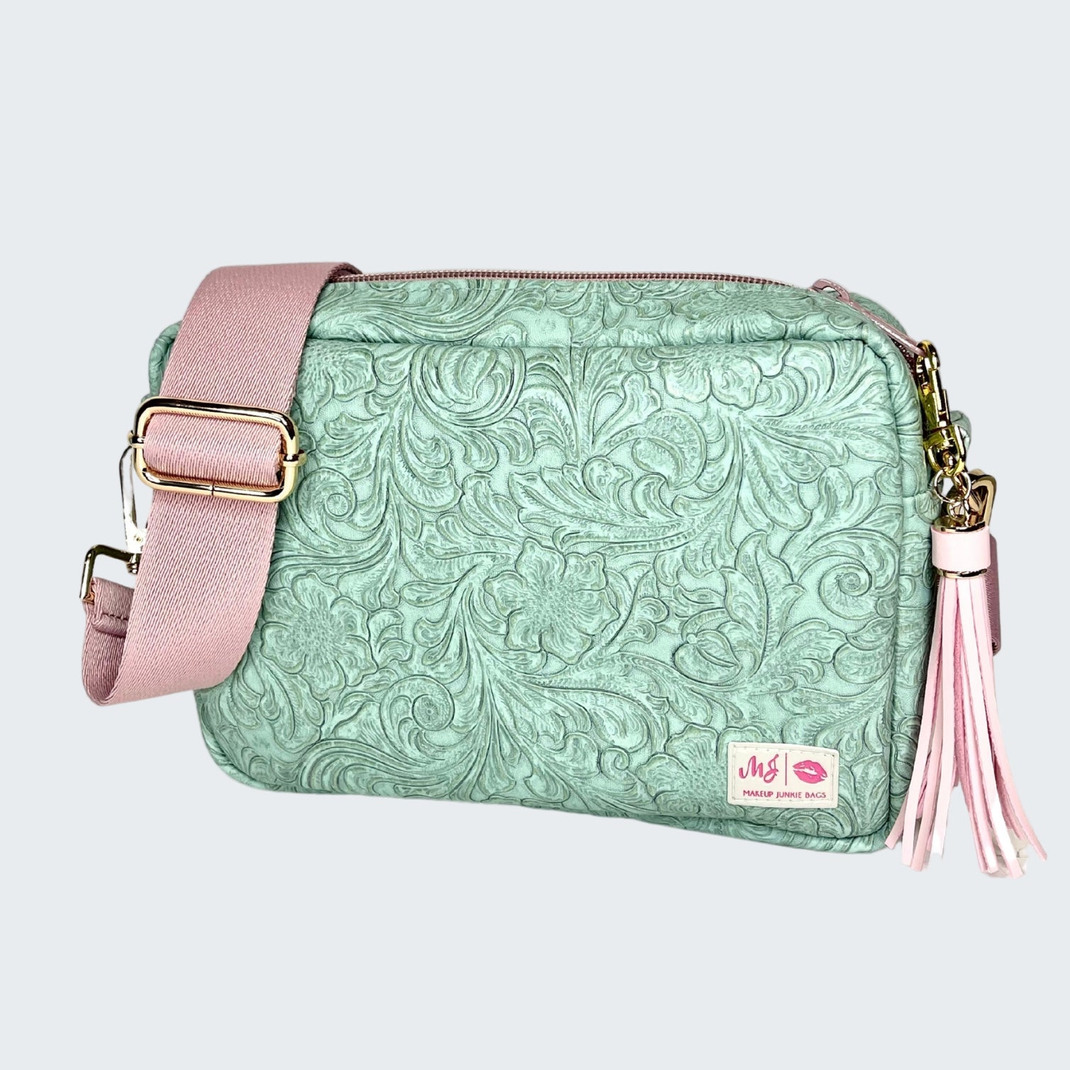 Green textured handbag with pink strap and tassel on a white background