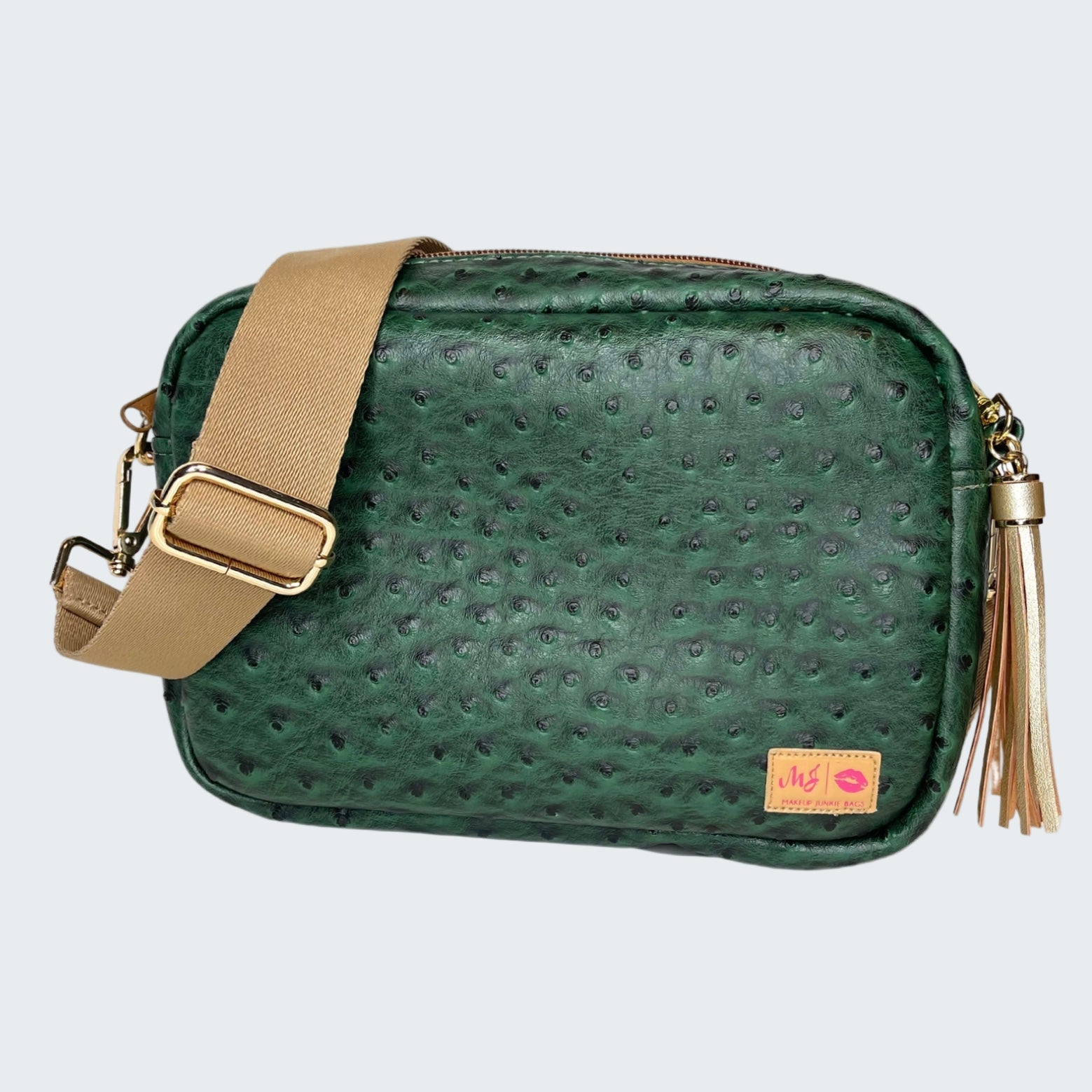 Green textured handbag with beige strap and tassel on a white background