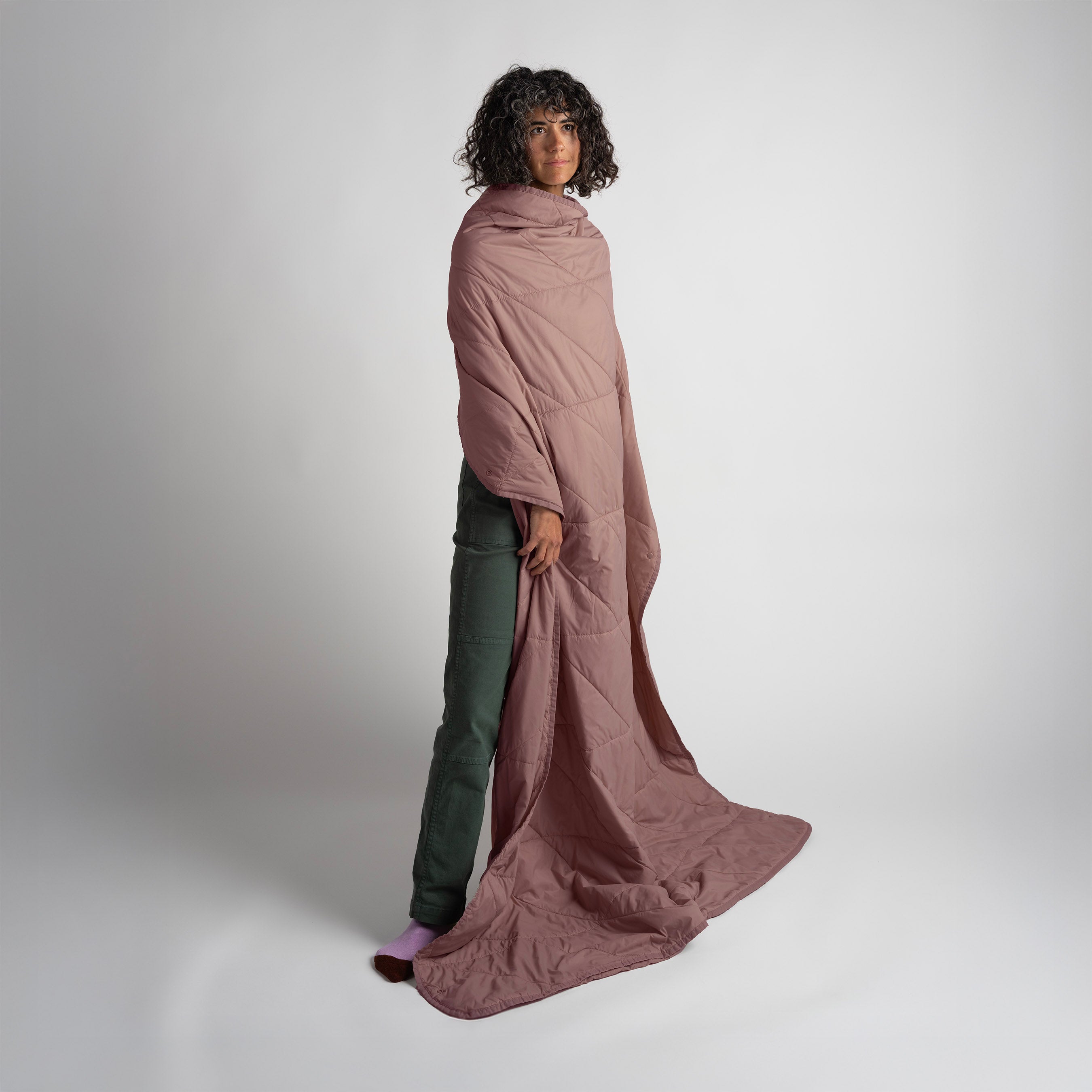 Person wearing a long, flowing pink garment against a plain background