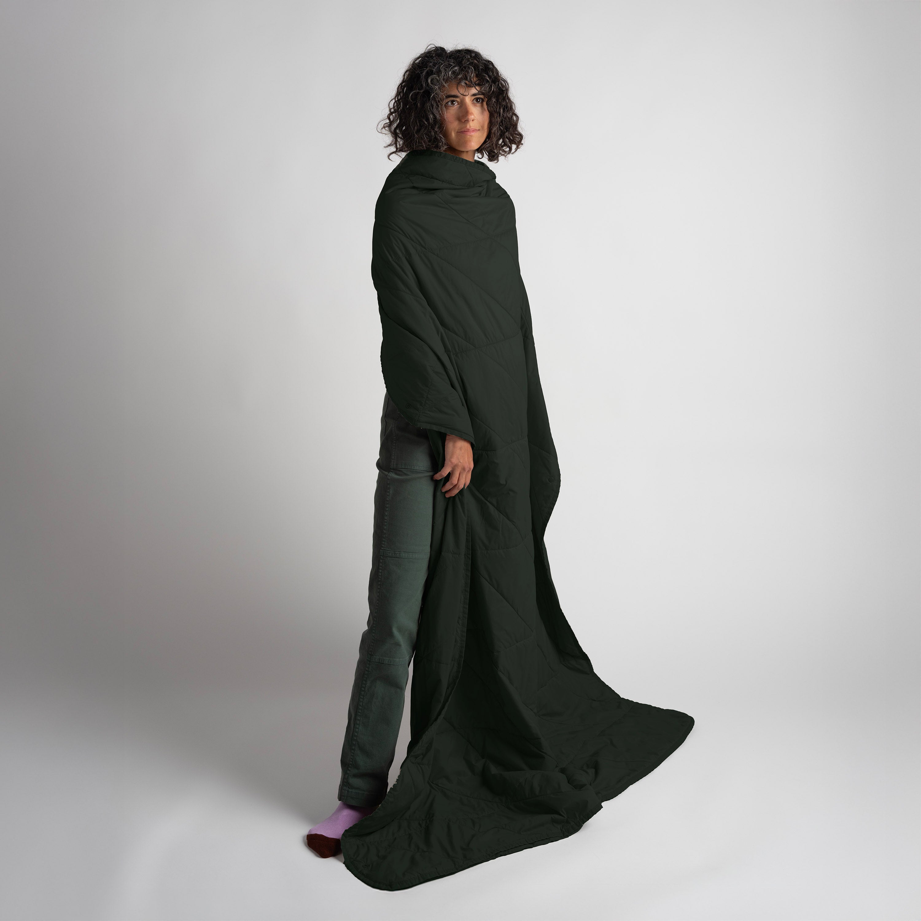 Person wearing a long, dark green garment against a plain background