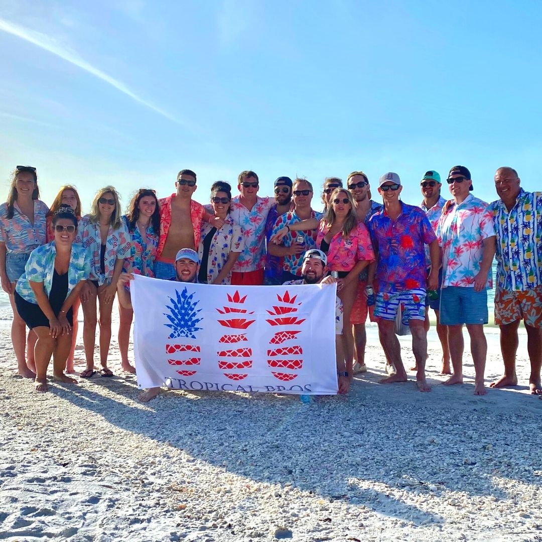 Group of people on a beach holding a 'Tropical Trash' banner