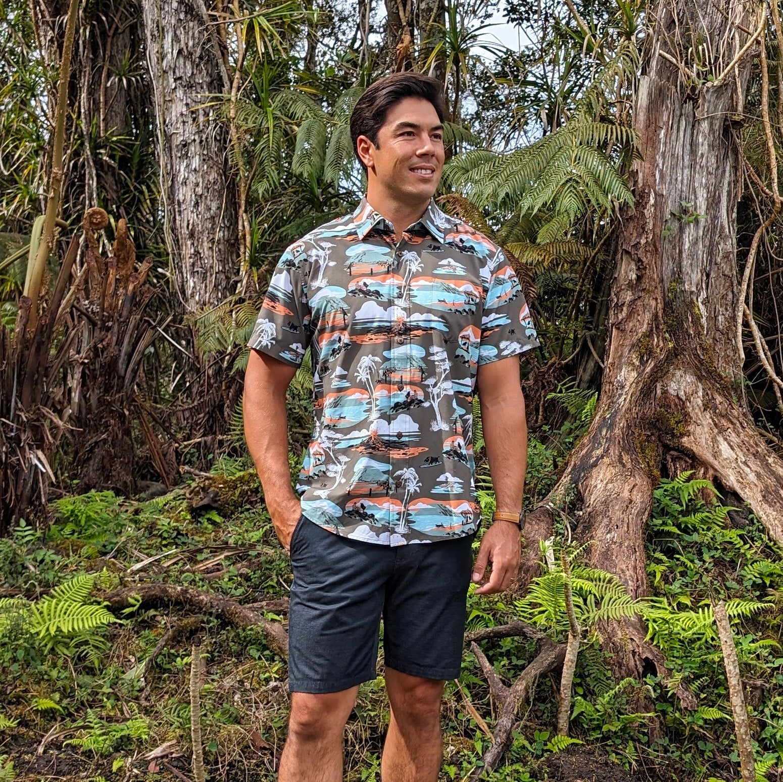 Man wearing a patterned shirt and shorts standing in a forest