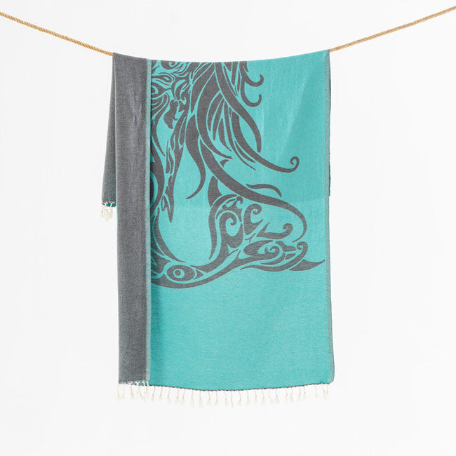 Turquoise towel with gray pattern hanging on a line against a white background