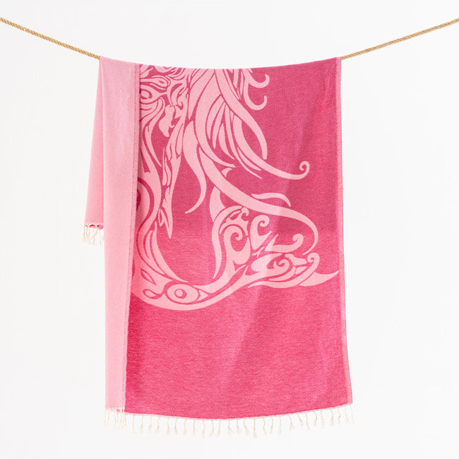 Pink towel with white abstract design hanging on a line against a white background