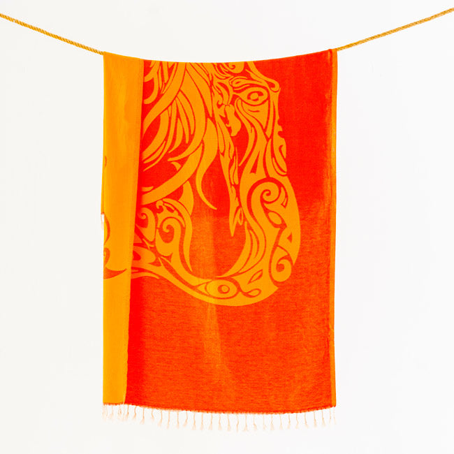 Orange towel with yellow dragon design hanging on a line