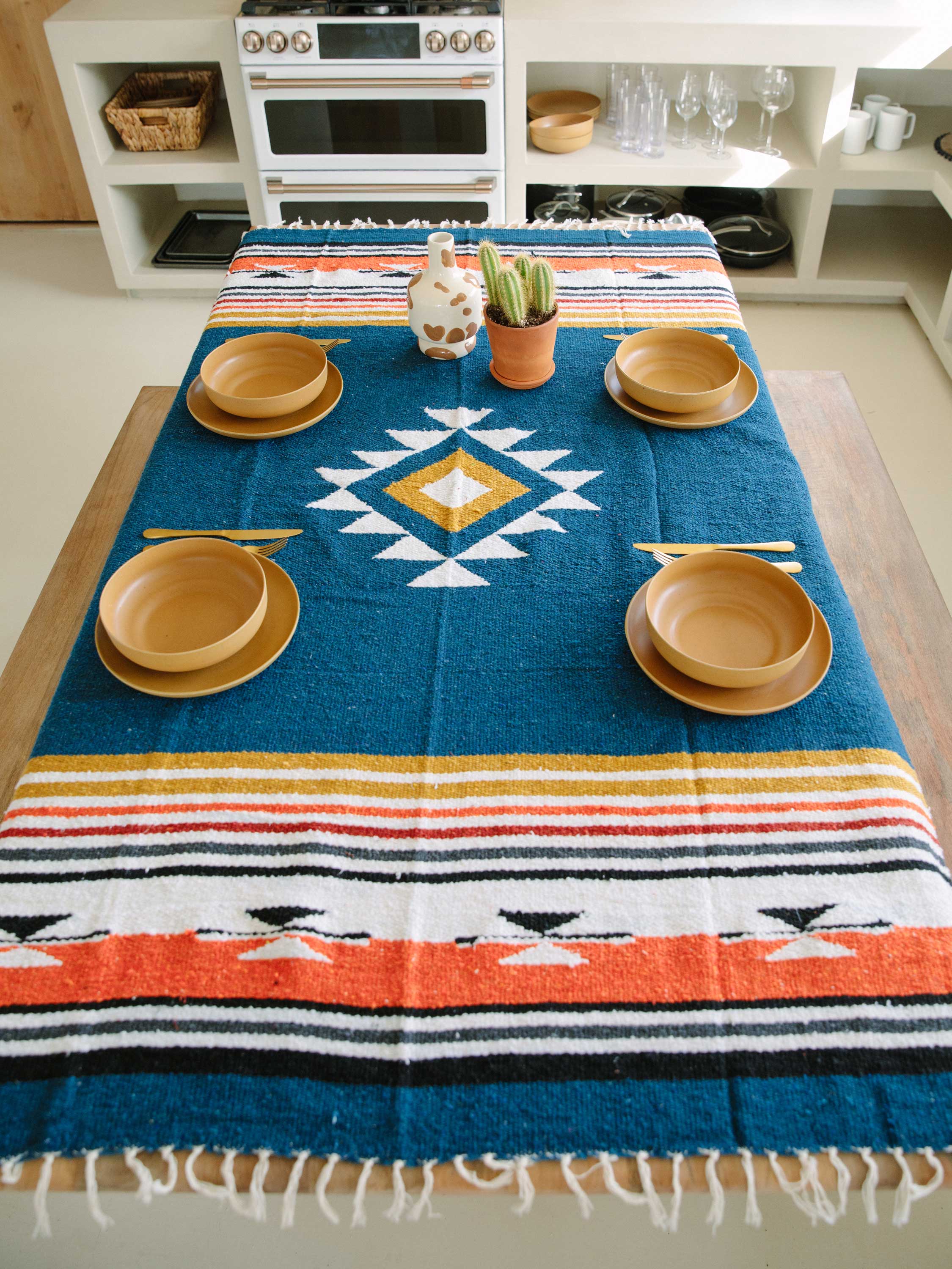 Table setting with a colorful patterned tablecloth in a kitchen.