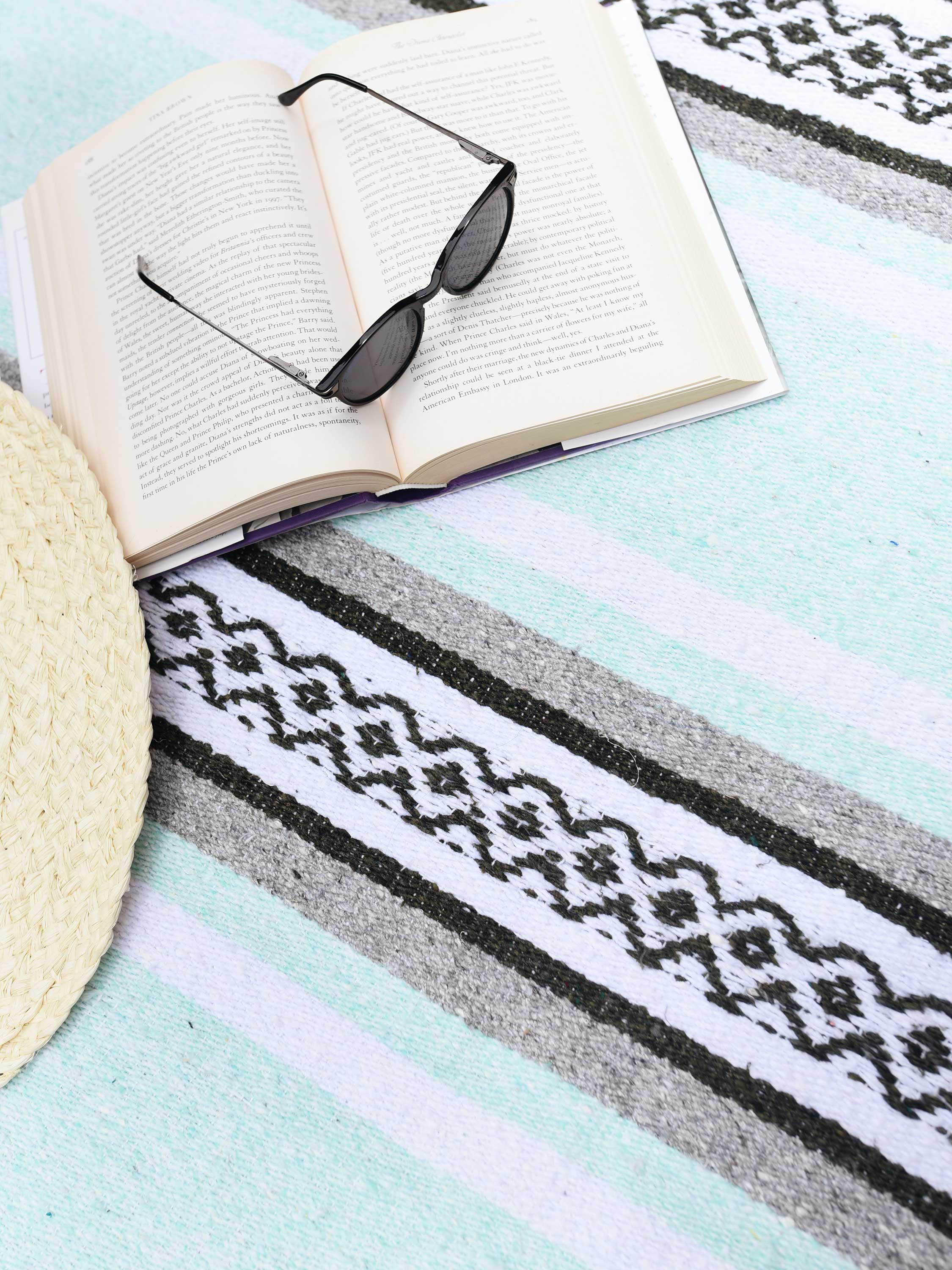 Open book with sunglasses on a patterned towel