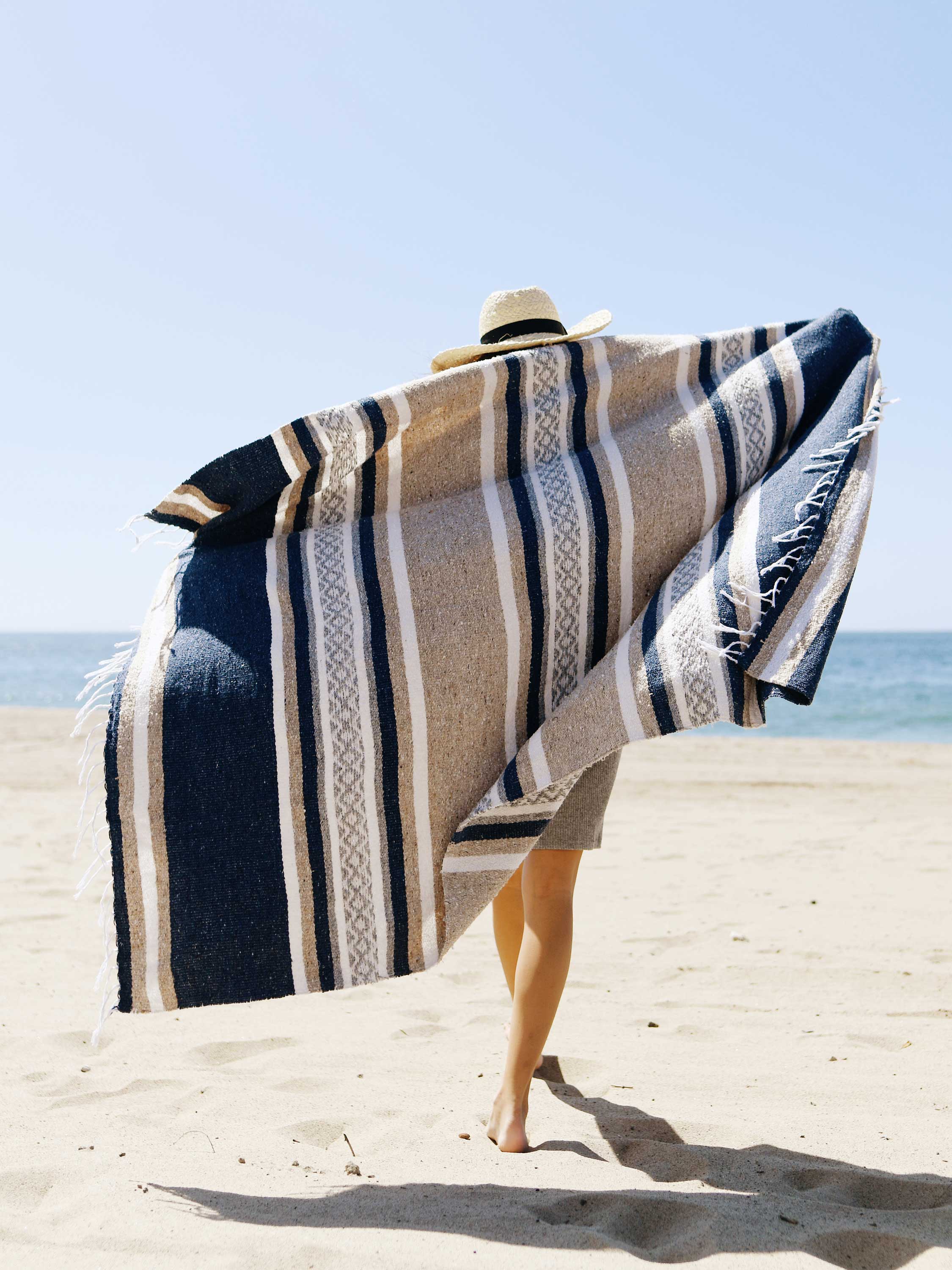 Person on a beach with a striped towel draped over their shoulders