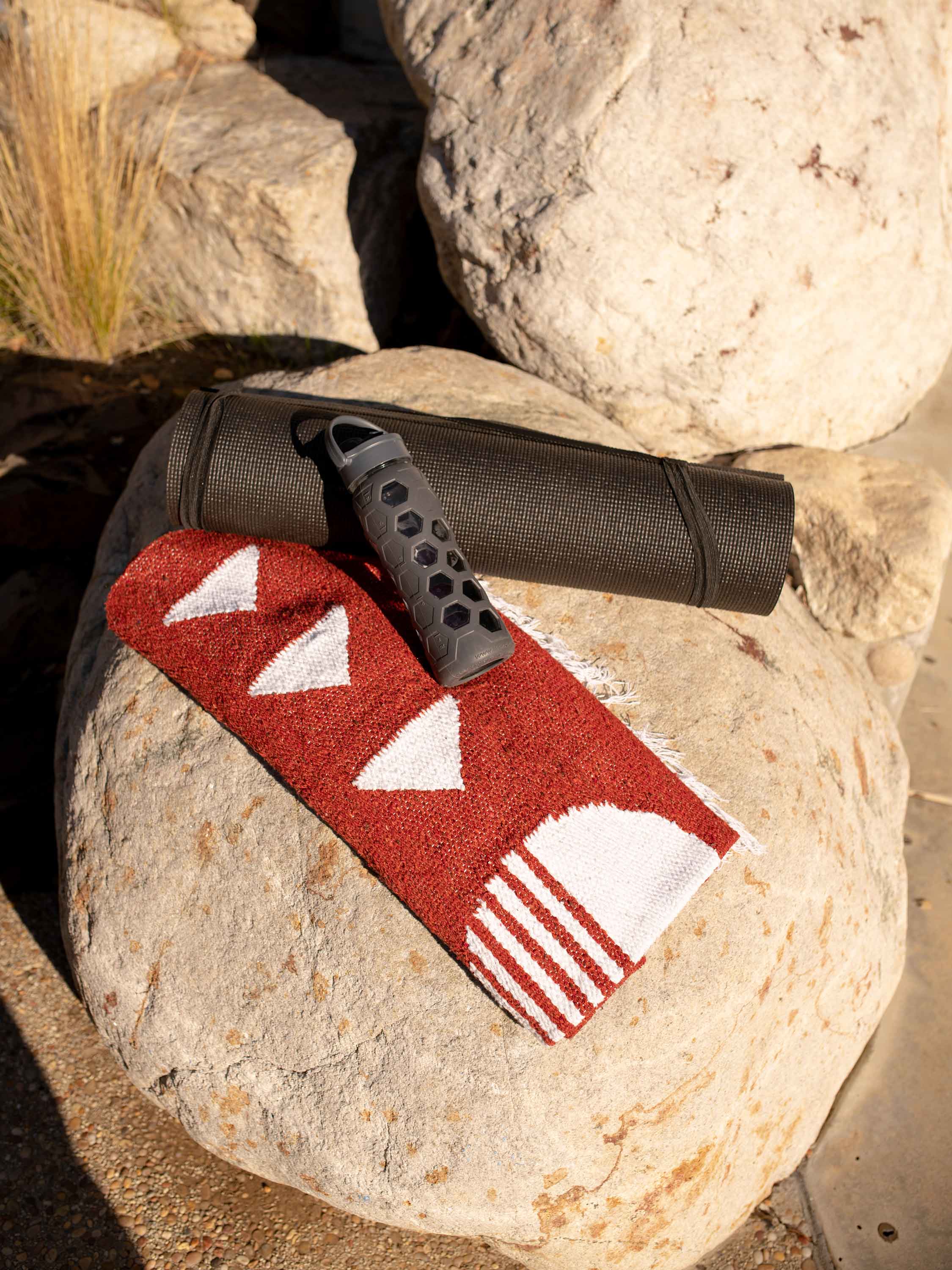 Red and white patterned mat with black handle on a rock
