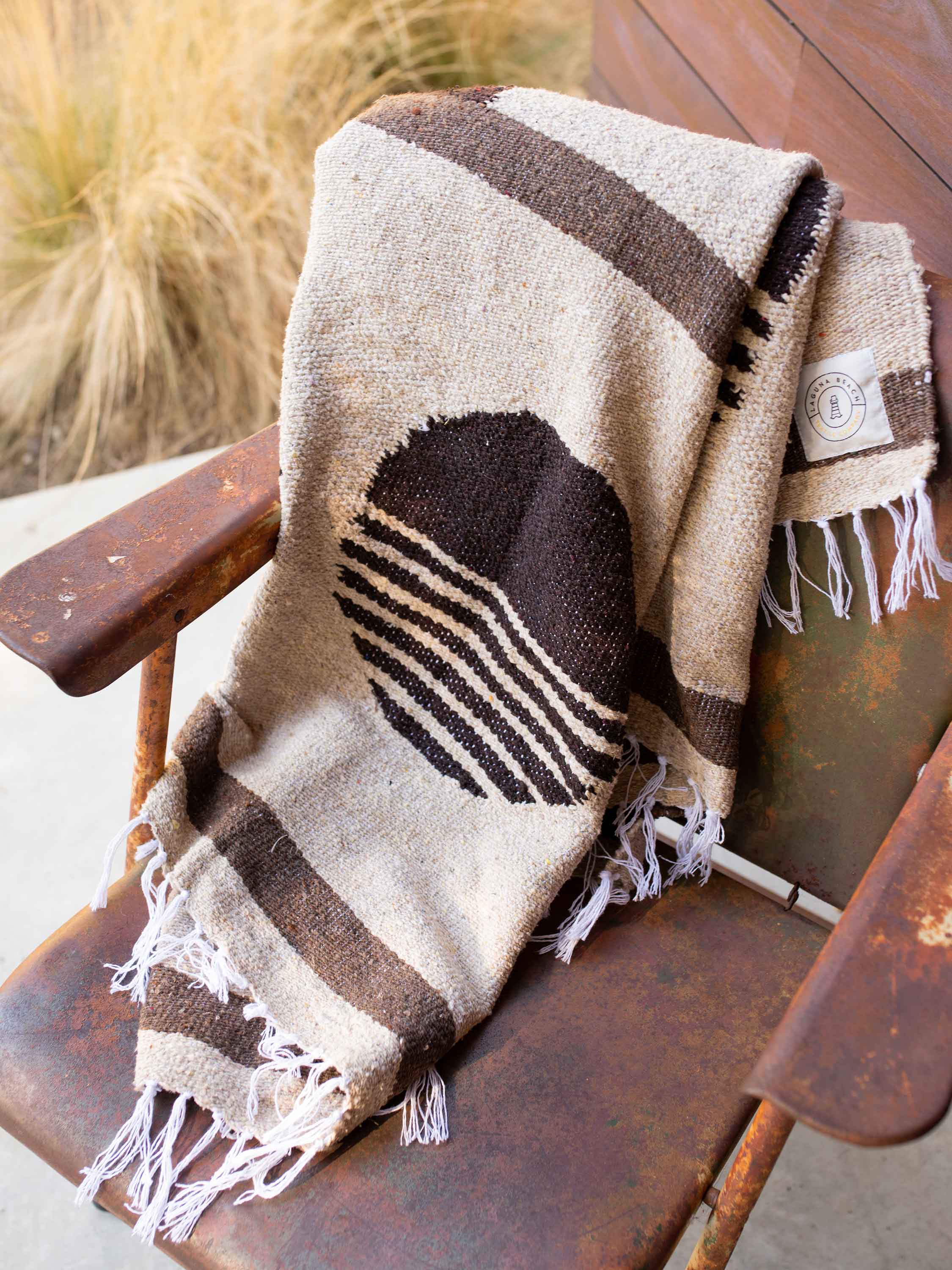 Woven blanket with geometric pattern draped over a wooden chair outdoors