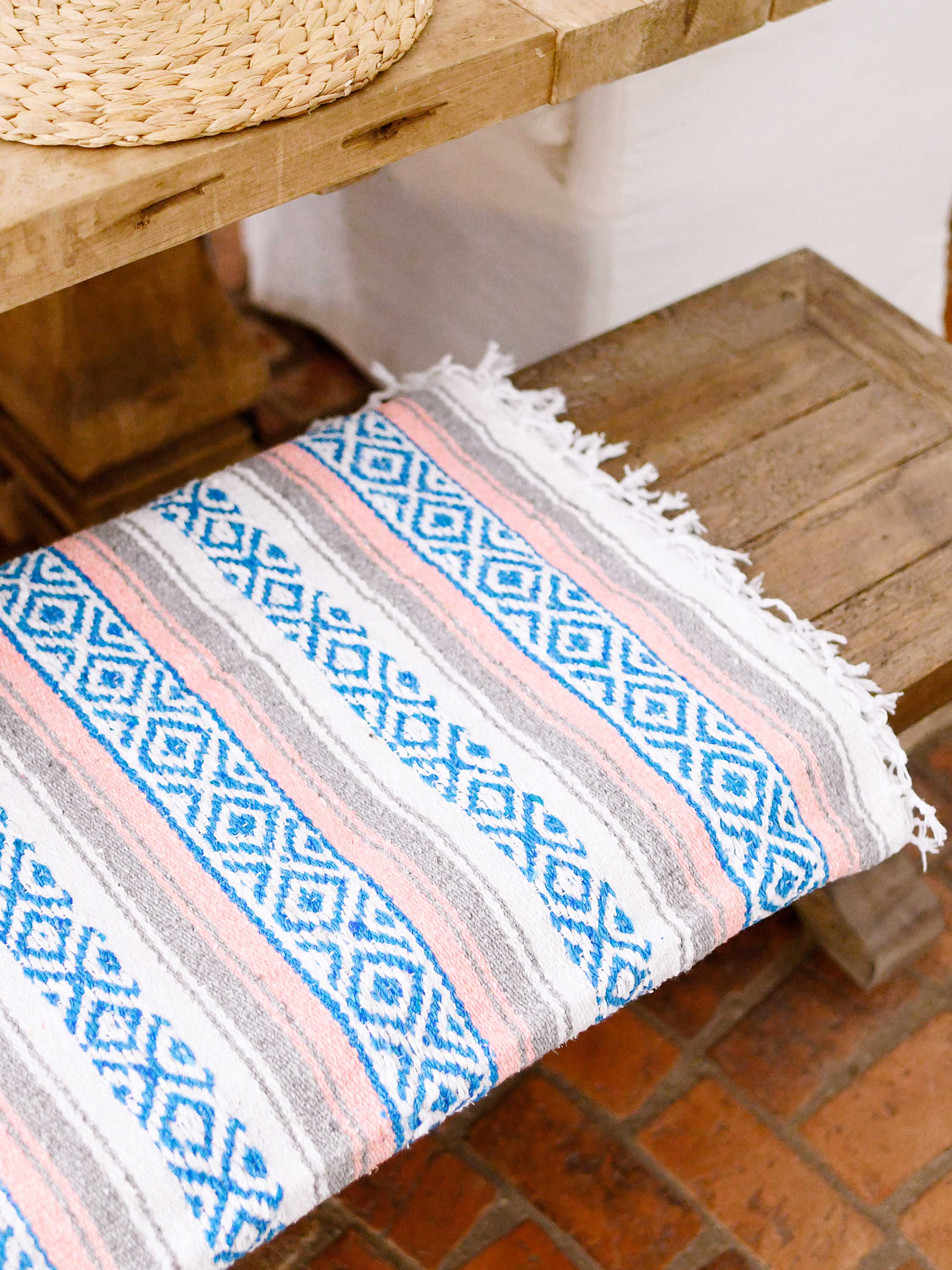 Patterned fabric on a wooden stool with a wicker chair in the background