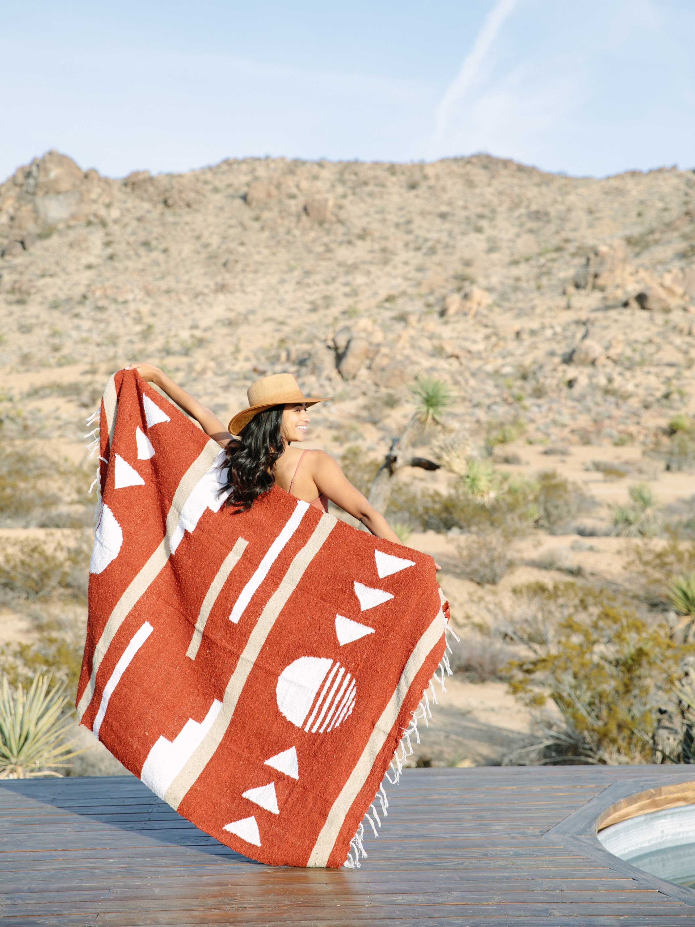 Person sitting on a desert landscape with a patterned blanket