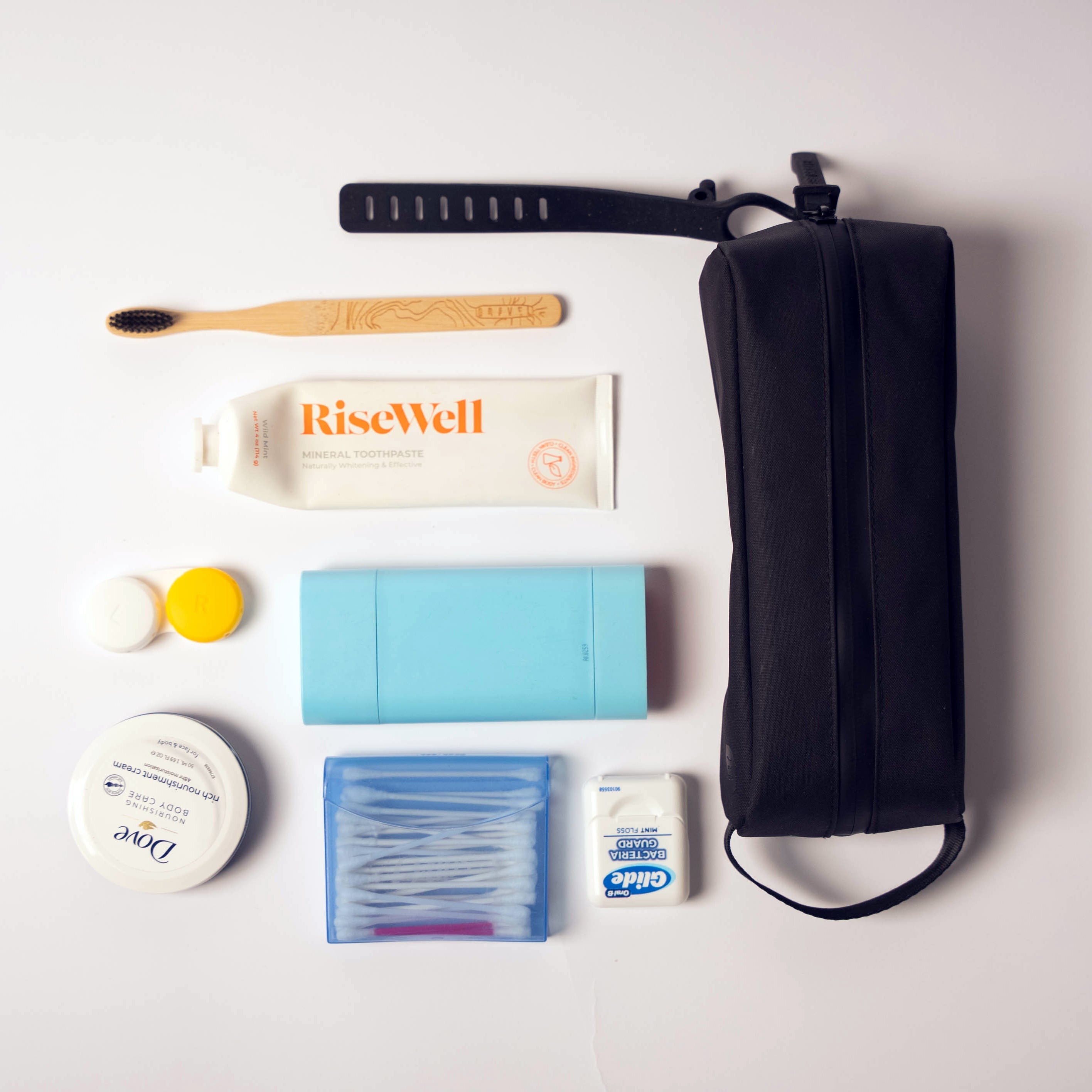 Collection of travel-sized toiletries and a black toiletry bag on a white background