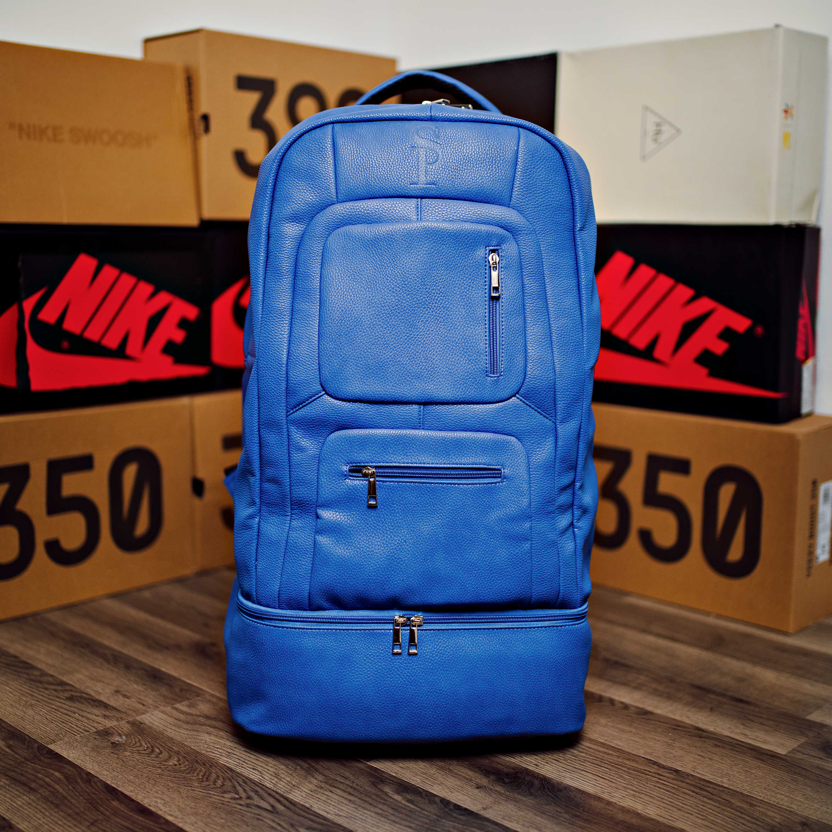 Blue backpack in front of Nike boxes on a wooden floor