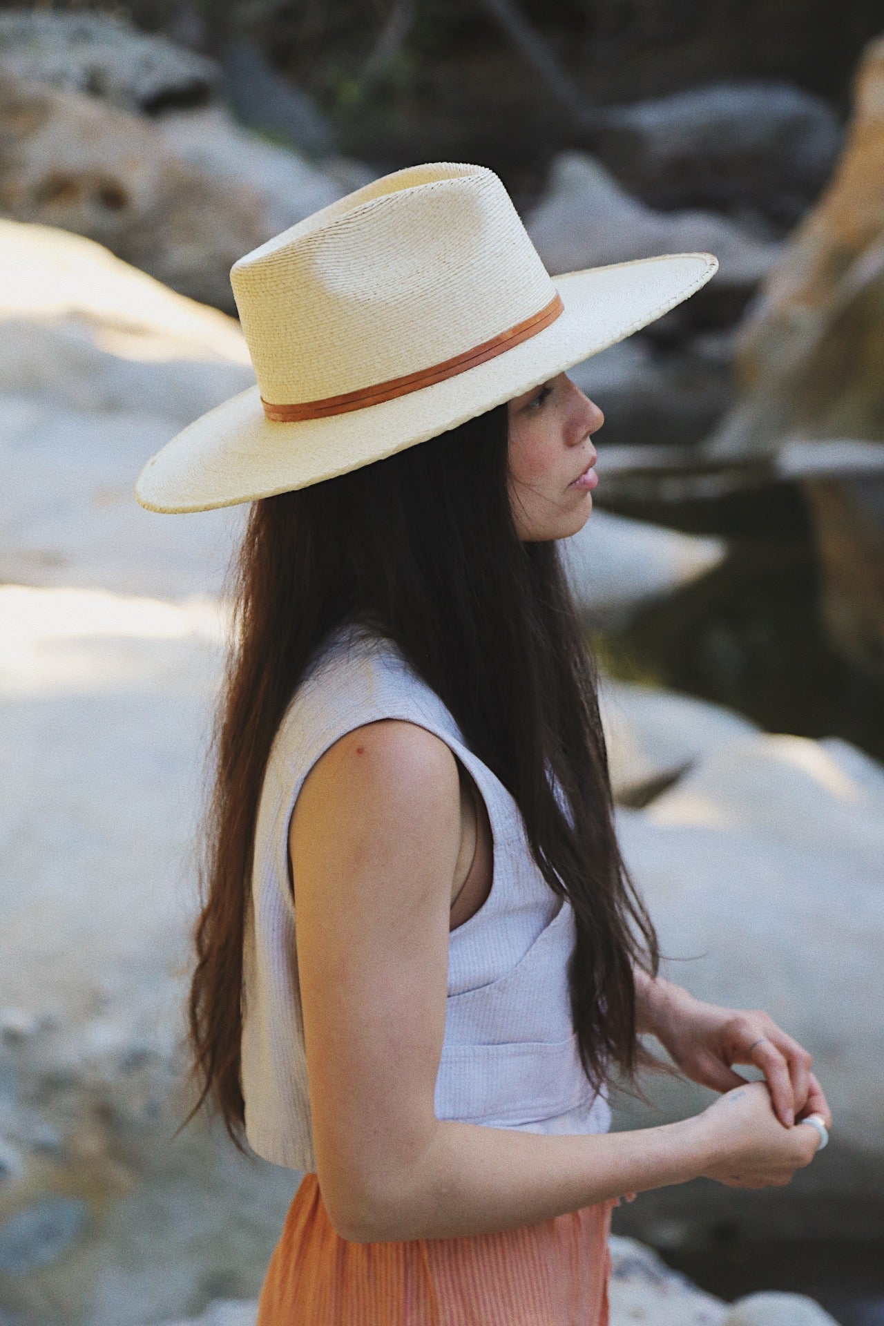Woman wearing a wide-brimmed hat by a rocky stream