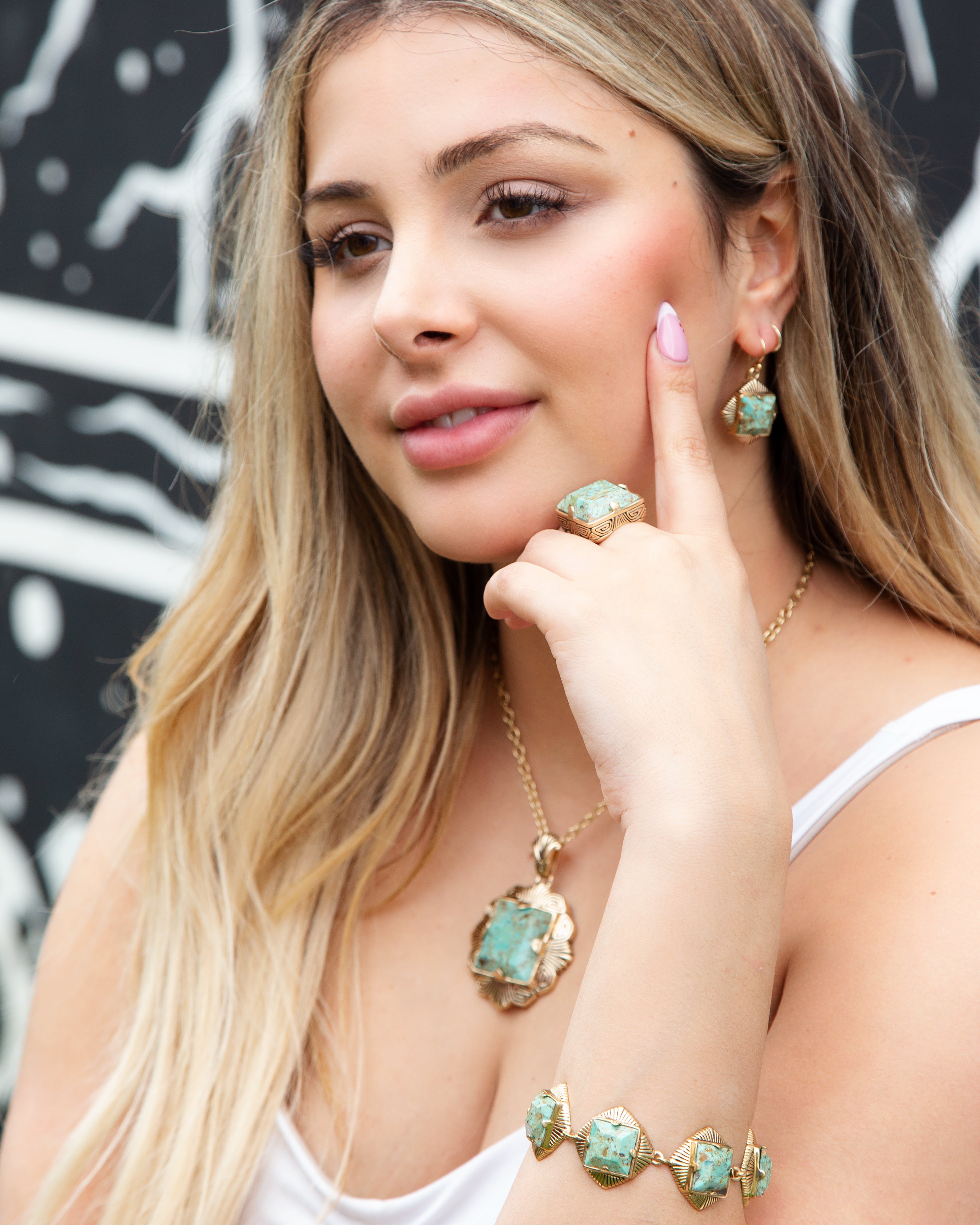 Woman wearing turquoise jewelry against a black and white abstract background