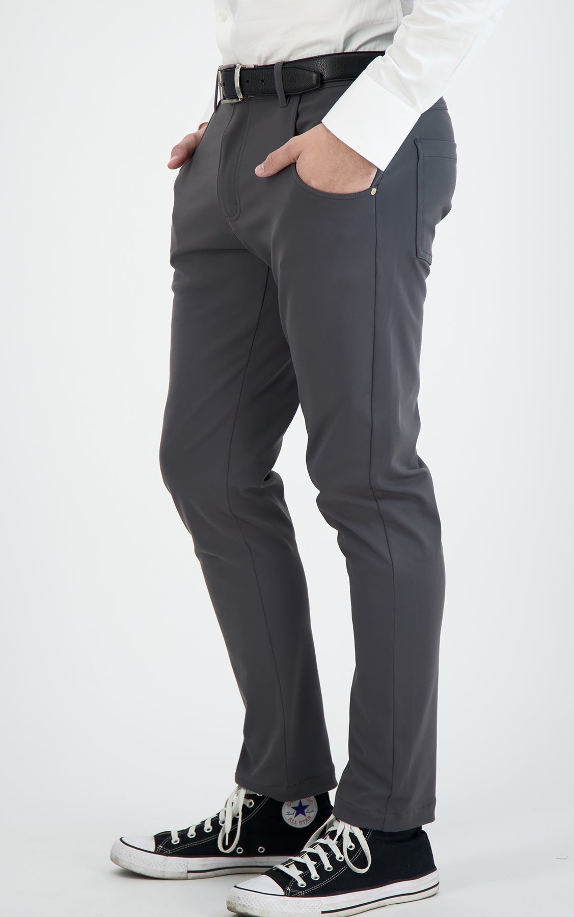Person wearing gray pants with a white shirt and black sneakers on a light gray background