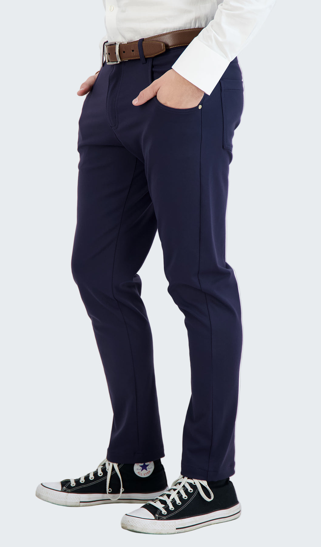 Person wearing navy pants with a white shirt and black sneakers on a white background