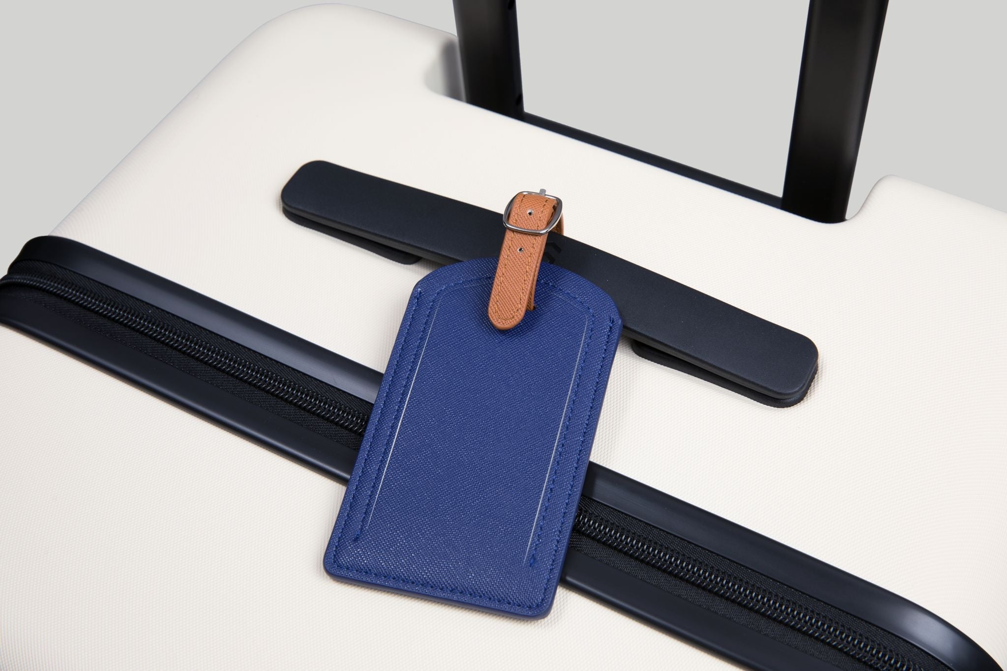 Blue luggage tag with brown strap on a white surface