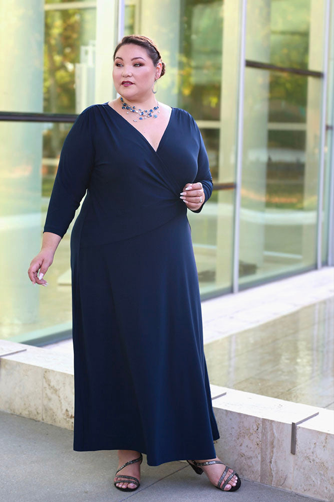 Woman wearing a navy blue dress standing outdoors with a glass building in the background