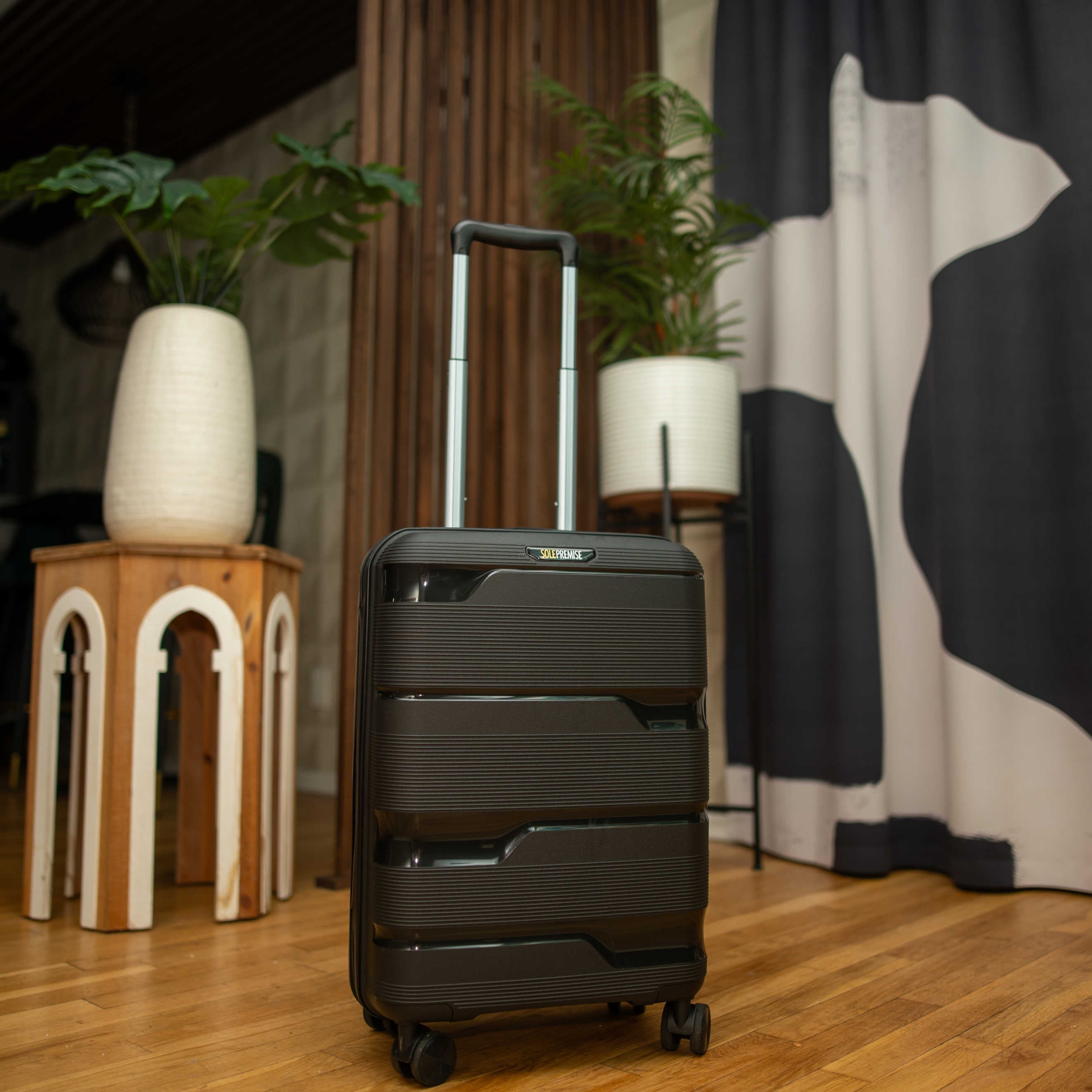 Black suitcase on a wooden floor with decorative elements in the background