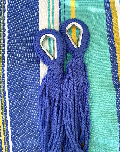 Blue rope with metal carabiners on a striped fabric background