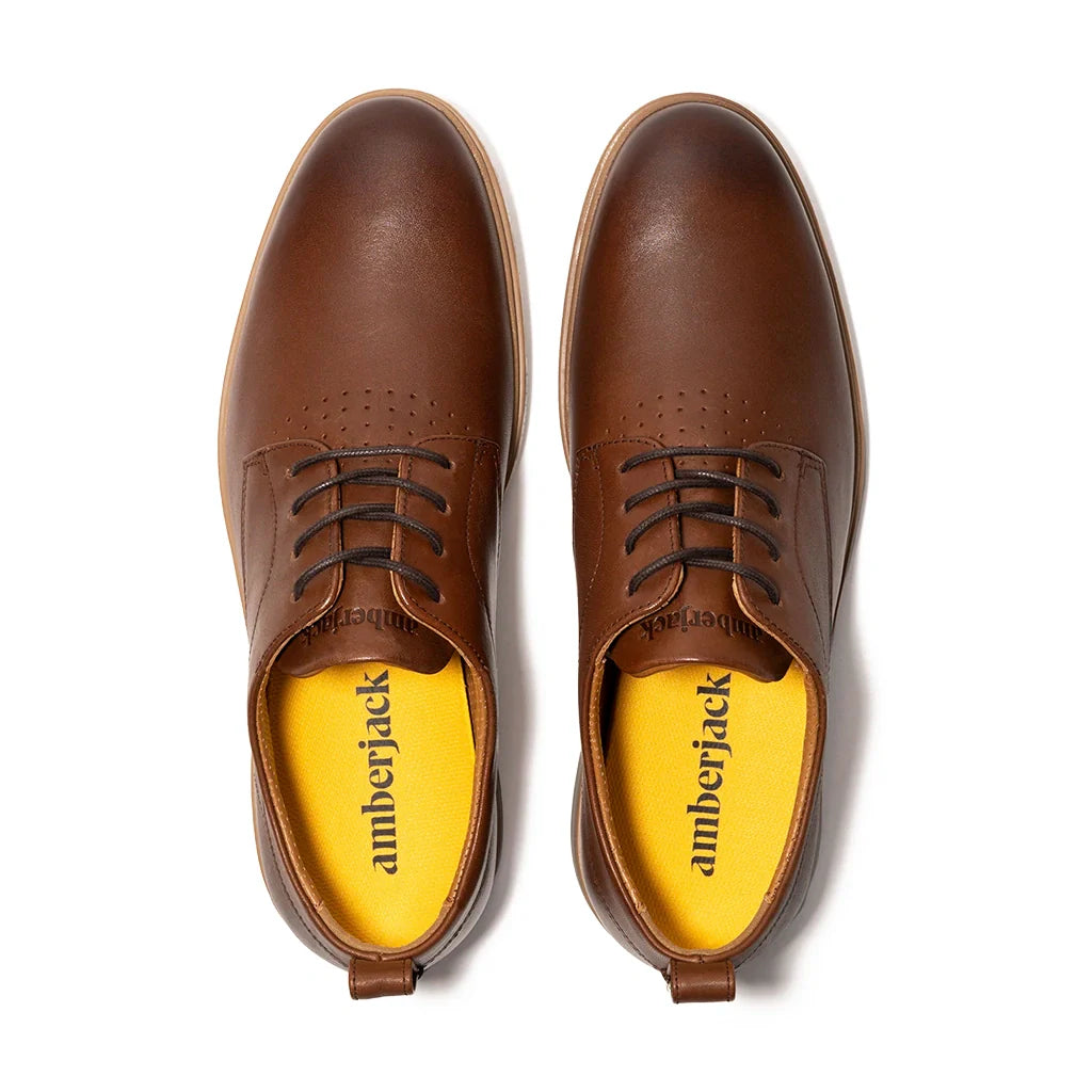 Brown leather shoes with yellow soles on a white background