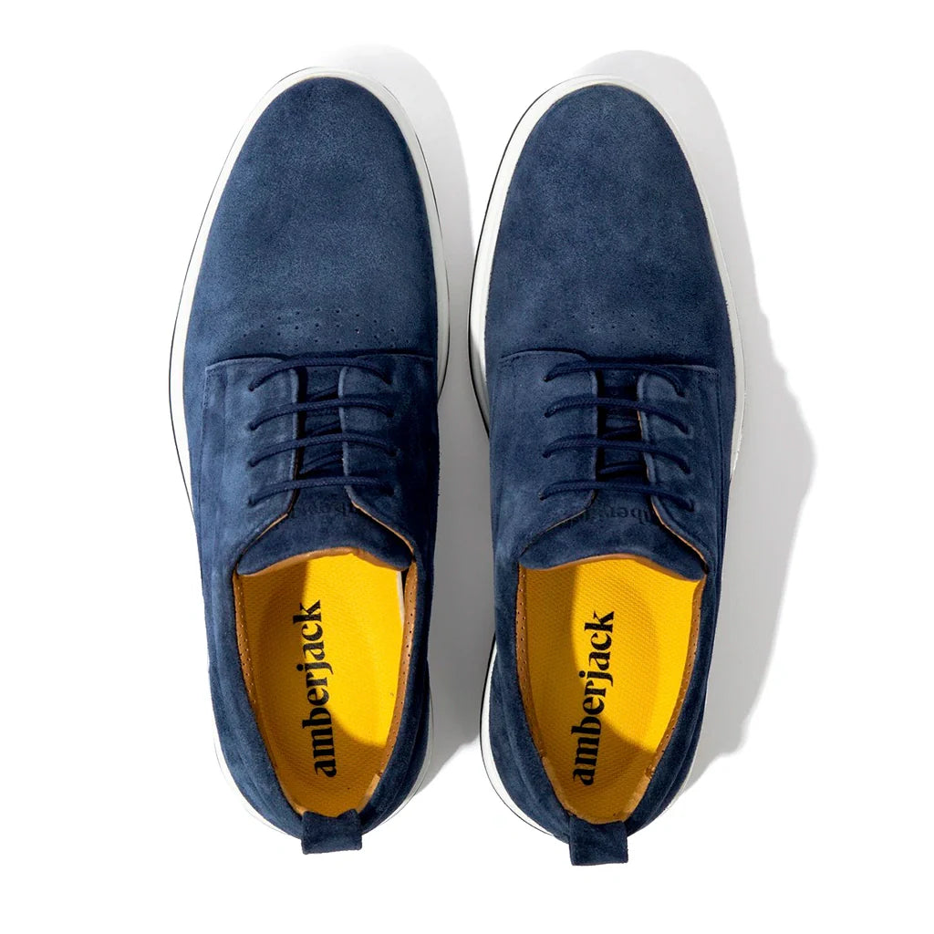 Pair of blue suede shoes with yellow lining on a white background