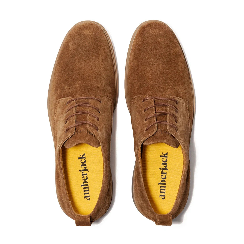 Pair of brown suede shoes with yellow interior on a white background
