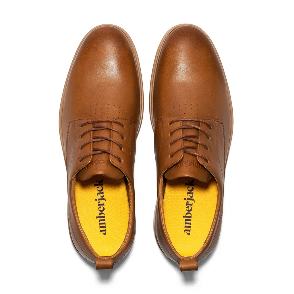 Pair of brown leather shoes with yellow interior on a white background