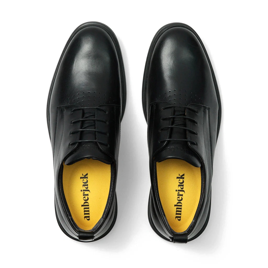 Black leather shoes with yellow soles on a white background