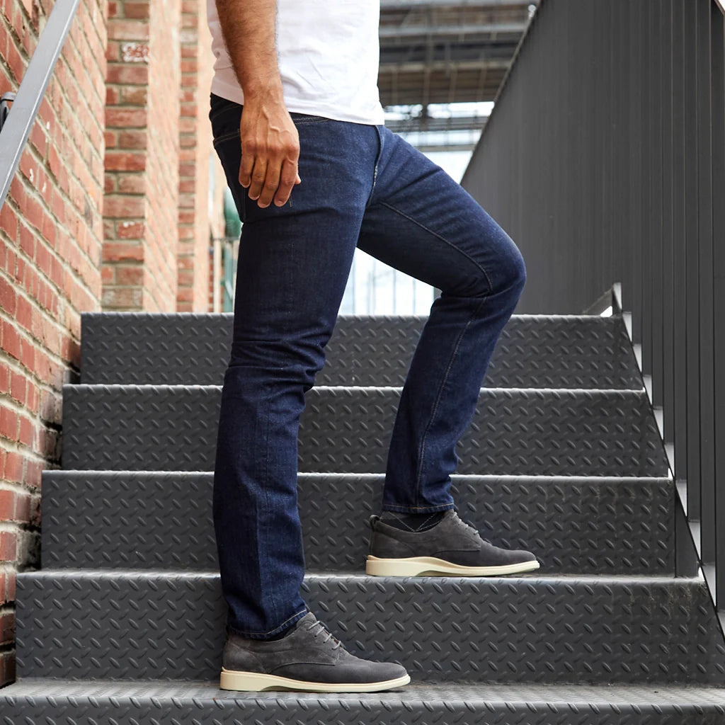 Person wearing blue jeans and black shoes climbing a set of stairs.