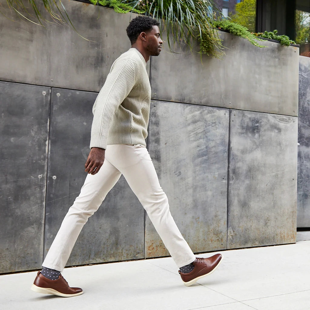Man walking outdoors against a concrete wall with plants