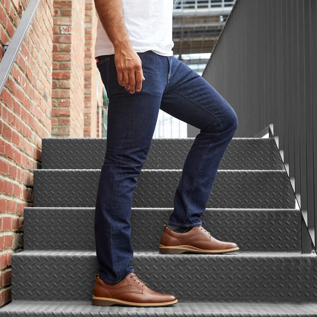 Person wearing blue jeans and brown shoes climbing stairs.