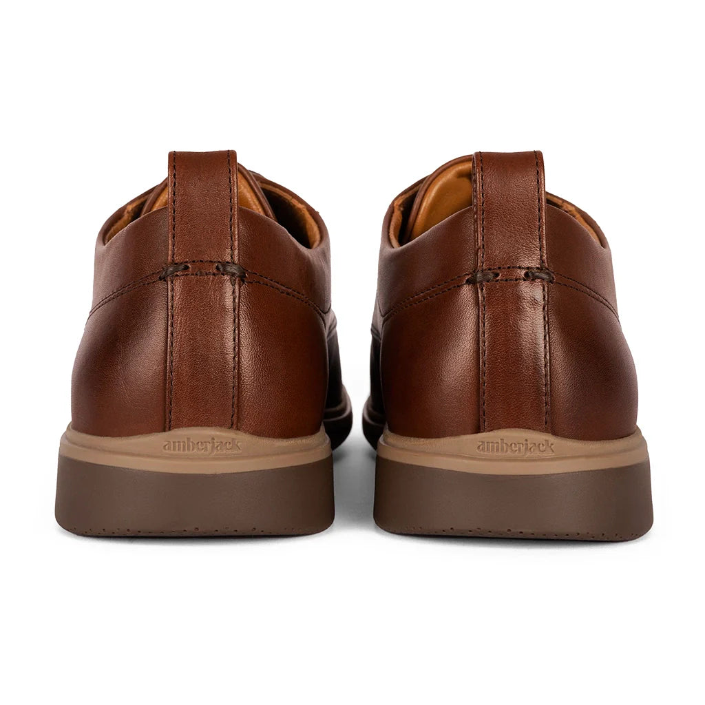 Pair of brown leather shoes with beige soles on a white background