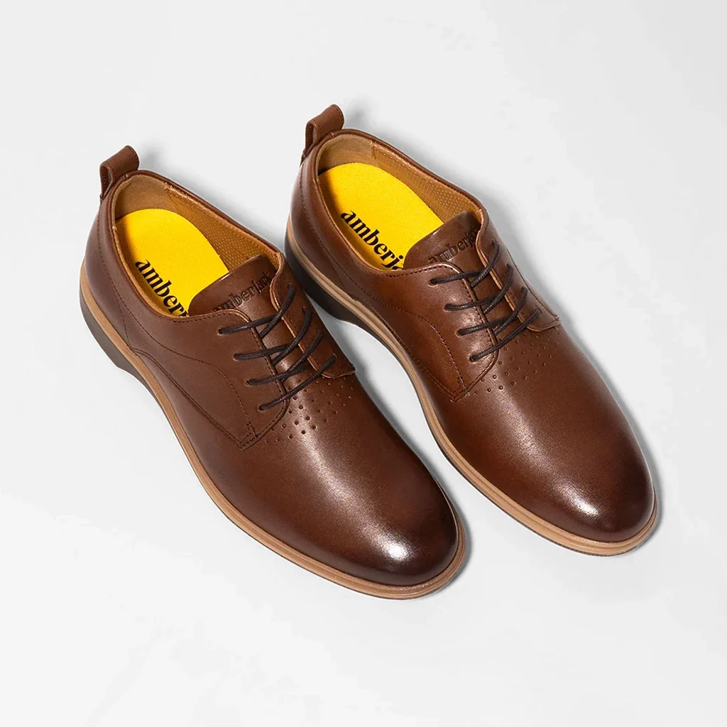 Pair of brown leather shoes with yellow lining on a white background