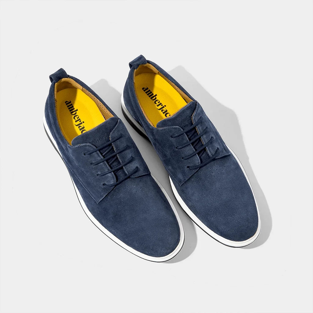 Pair of blue suede shoes with white soles on a light gray background