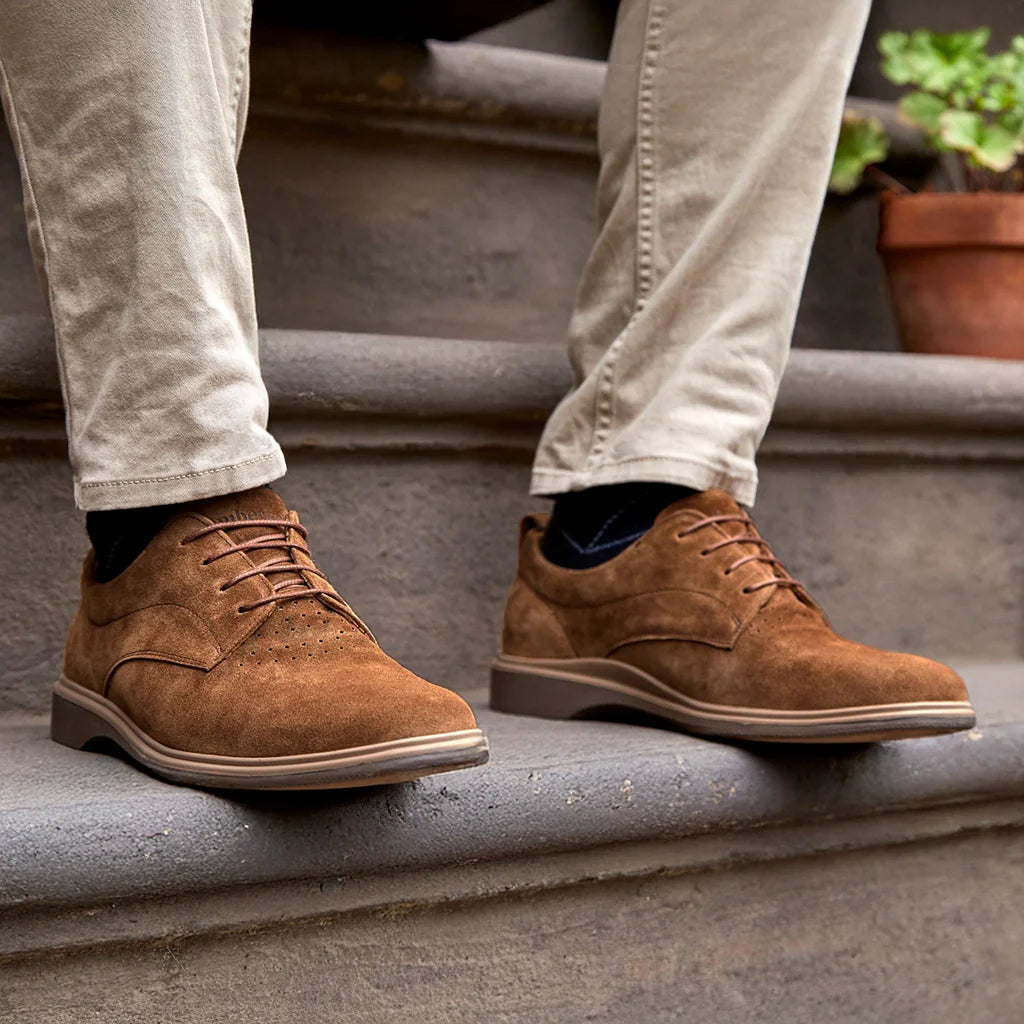Brown suede shoes worn on a person standing on concrete steps.