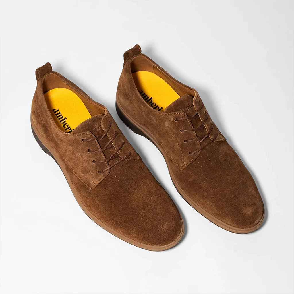 Pair of brown suede shoes with yellow lining on a white background