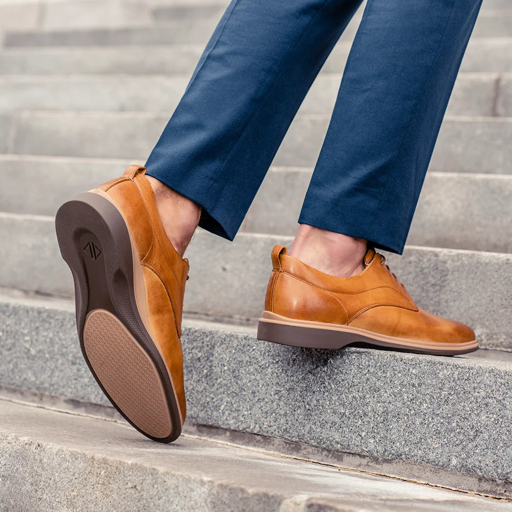 Brown leather shoes worn with blue pants on a staircase