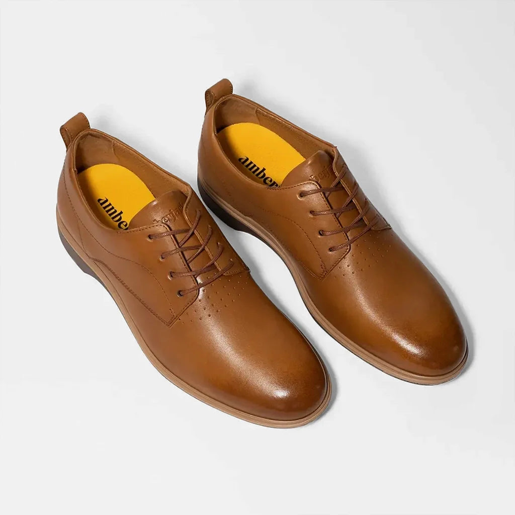 Pair of brown leather shoes with yellow lining on a white background