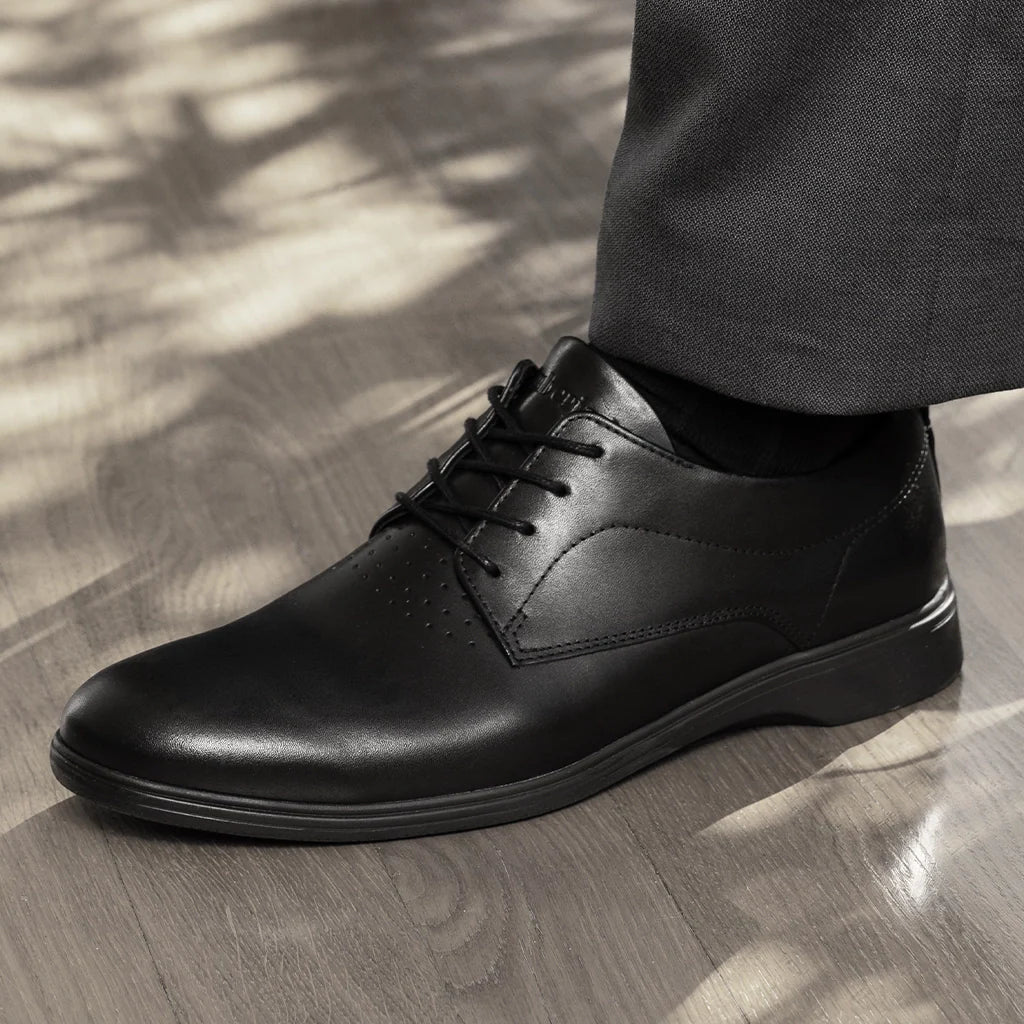 Black leather dress shoe on a wooden floor