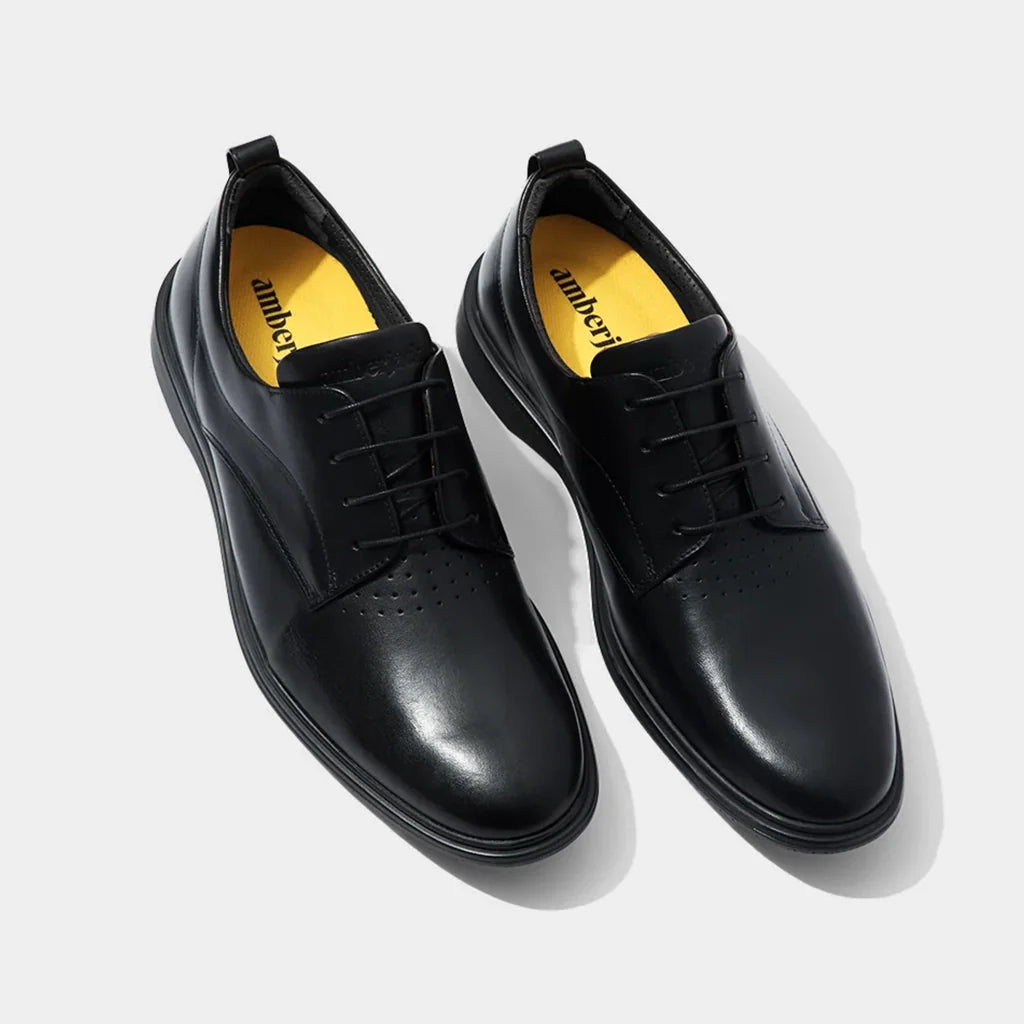 Pair of black dress shoes with yellow lining on a light gray background
