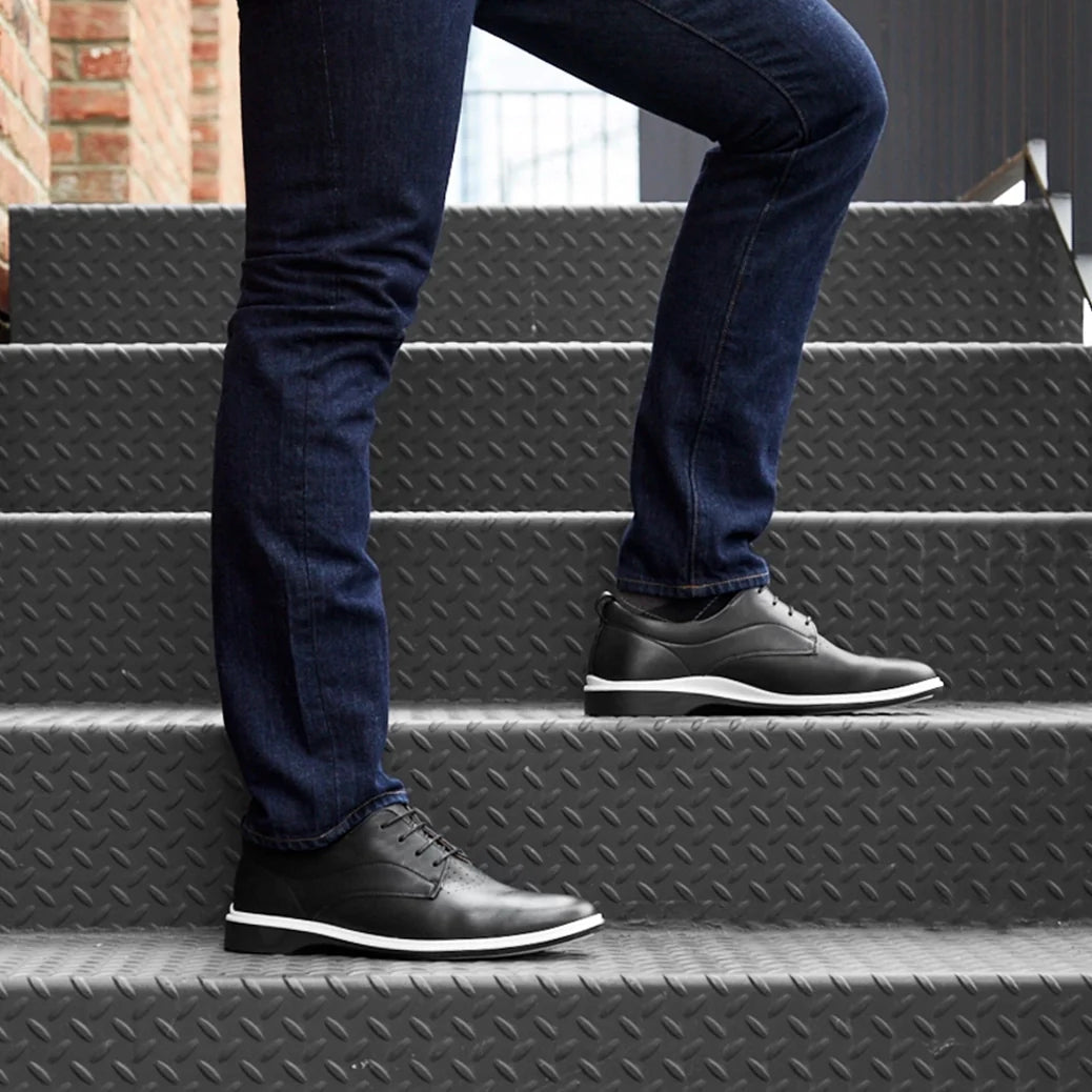 Person wearing black shoes and blue jeans stepping onto a set of gray stairs.
