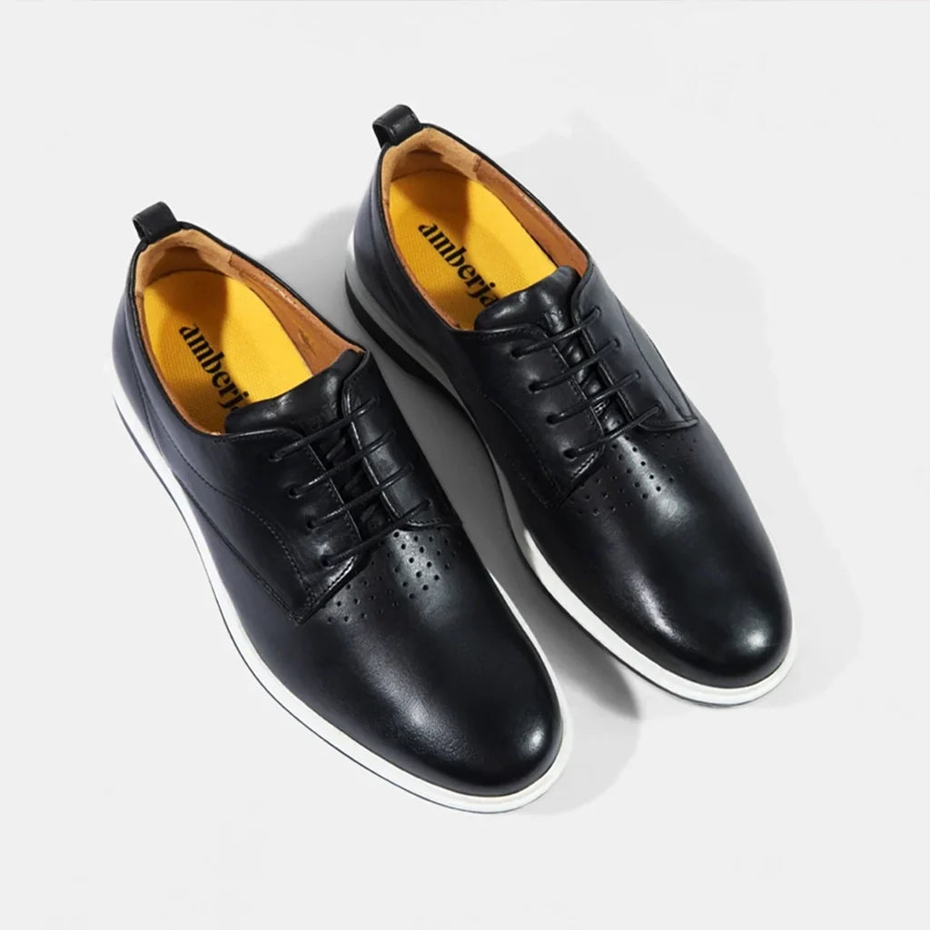 Black leather shoes with yellow lining on a white background