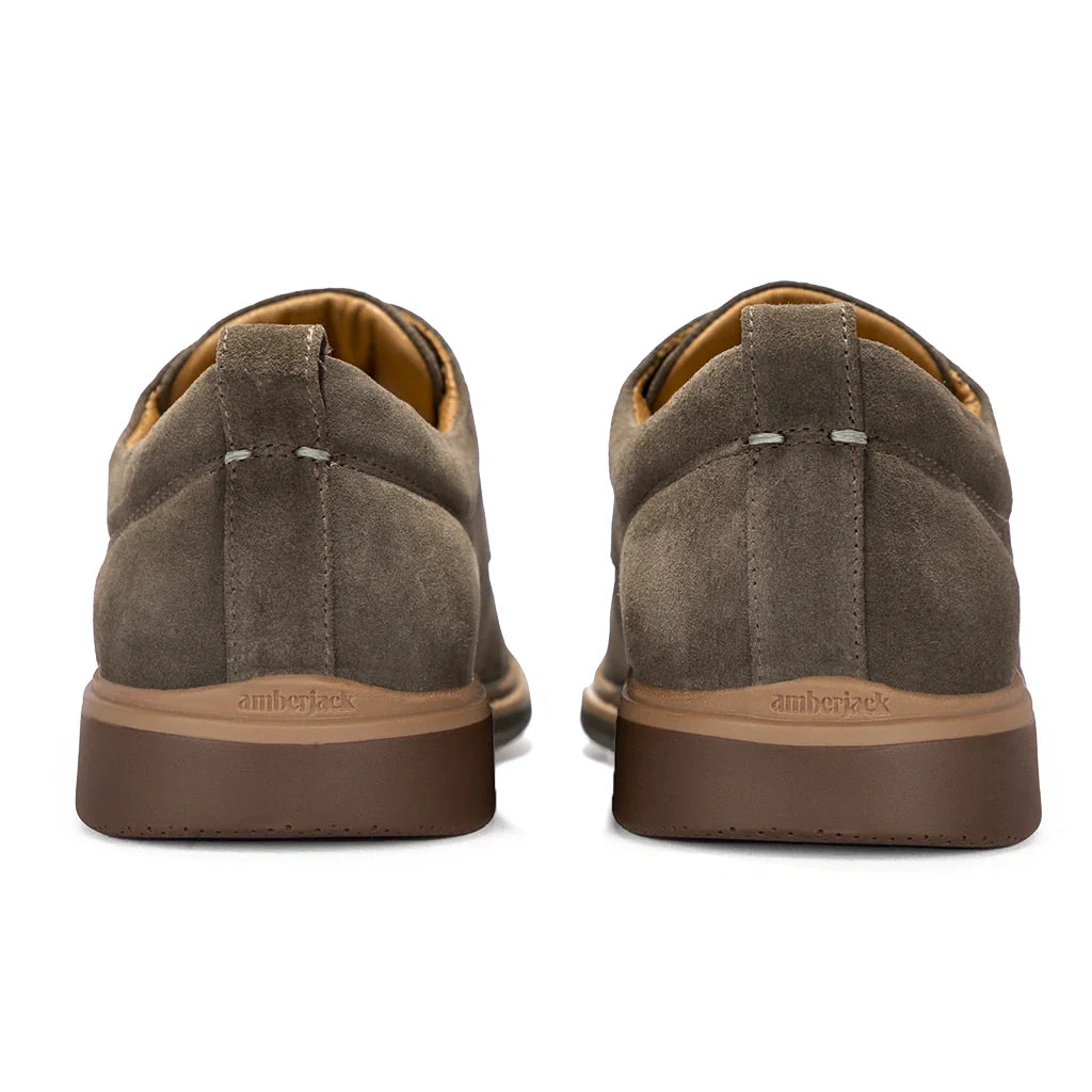 Brown suede shoes with brown soles on a white background