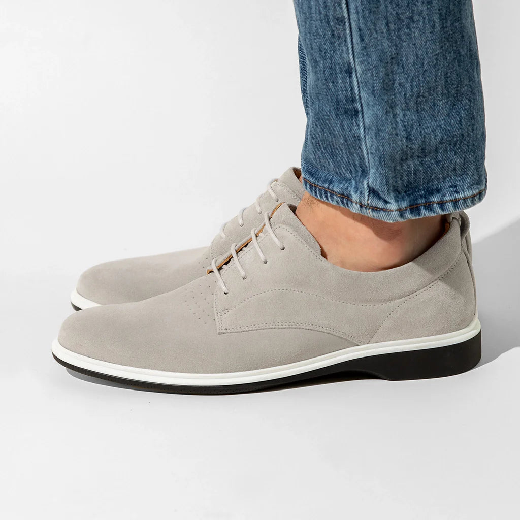 Gray suede shoes worn with blue jeans on a light gray background