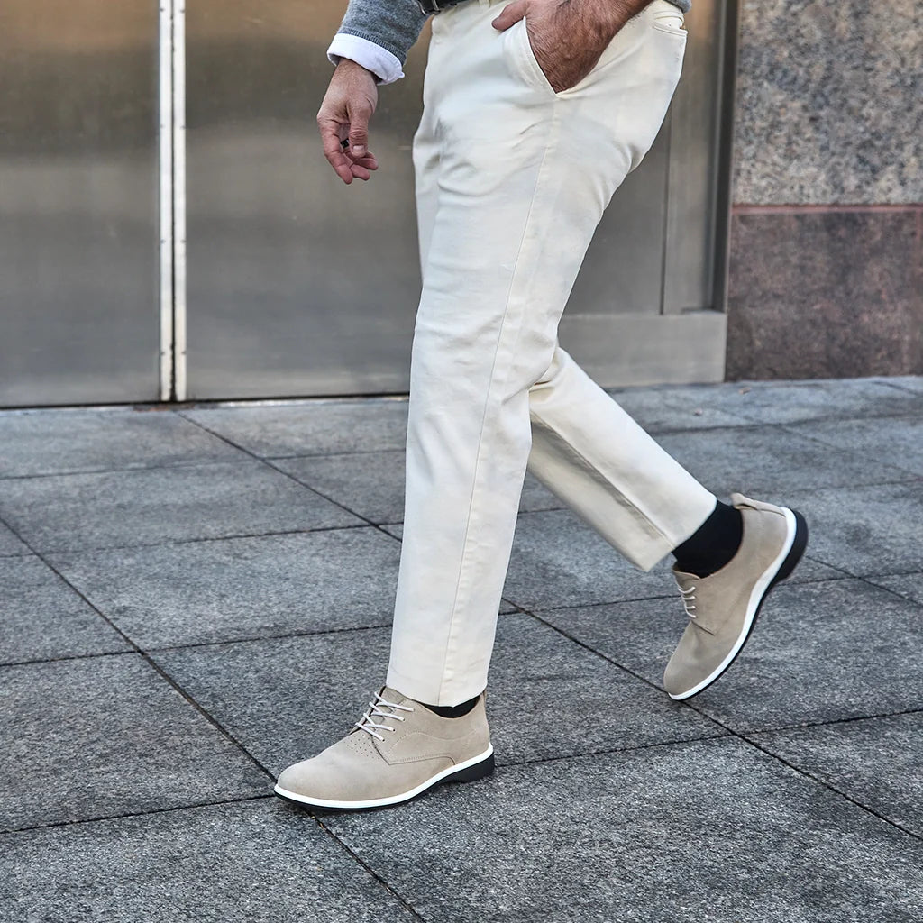 Person wearing beige shoes and white pants walking on a pavement.