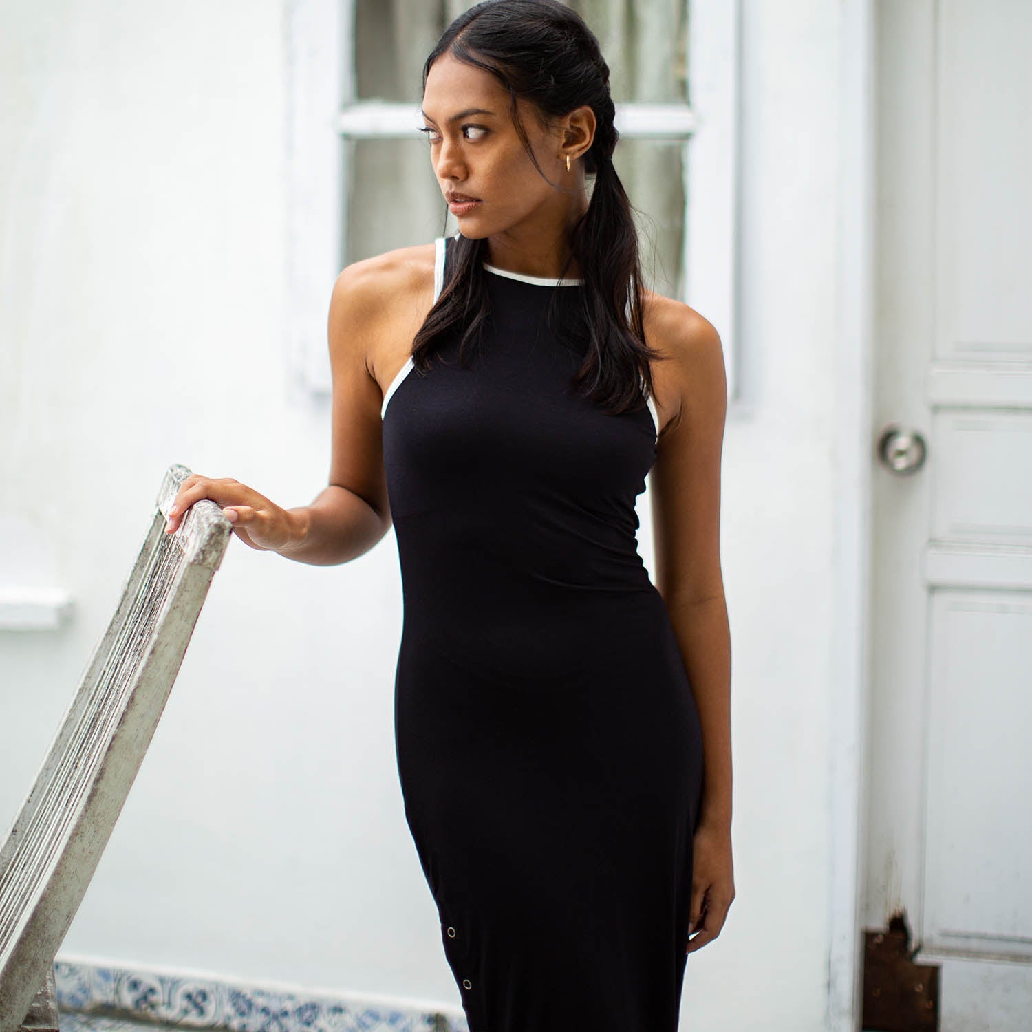 Woman in a black dress standing indoors with a neutral background
